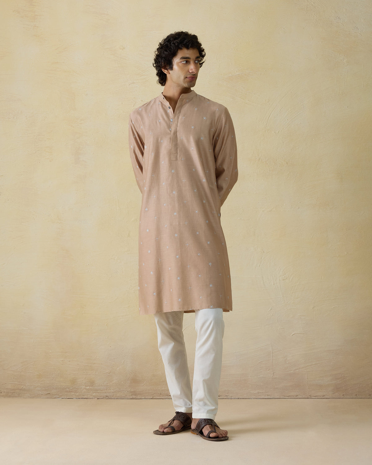 Person wearing a light beige neckband kurta with tiny embroidered motifs.