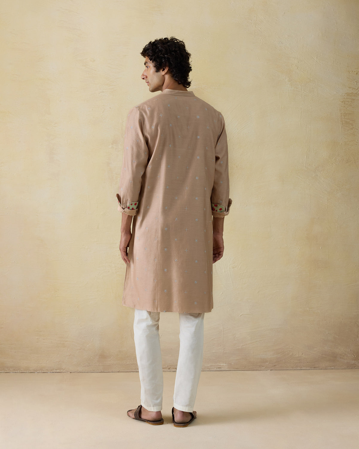 Back of a light beige neckband kurta with rolled sleeves.