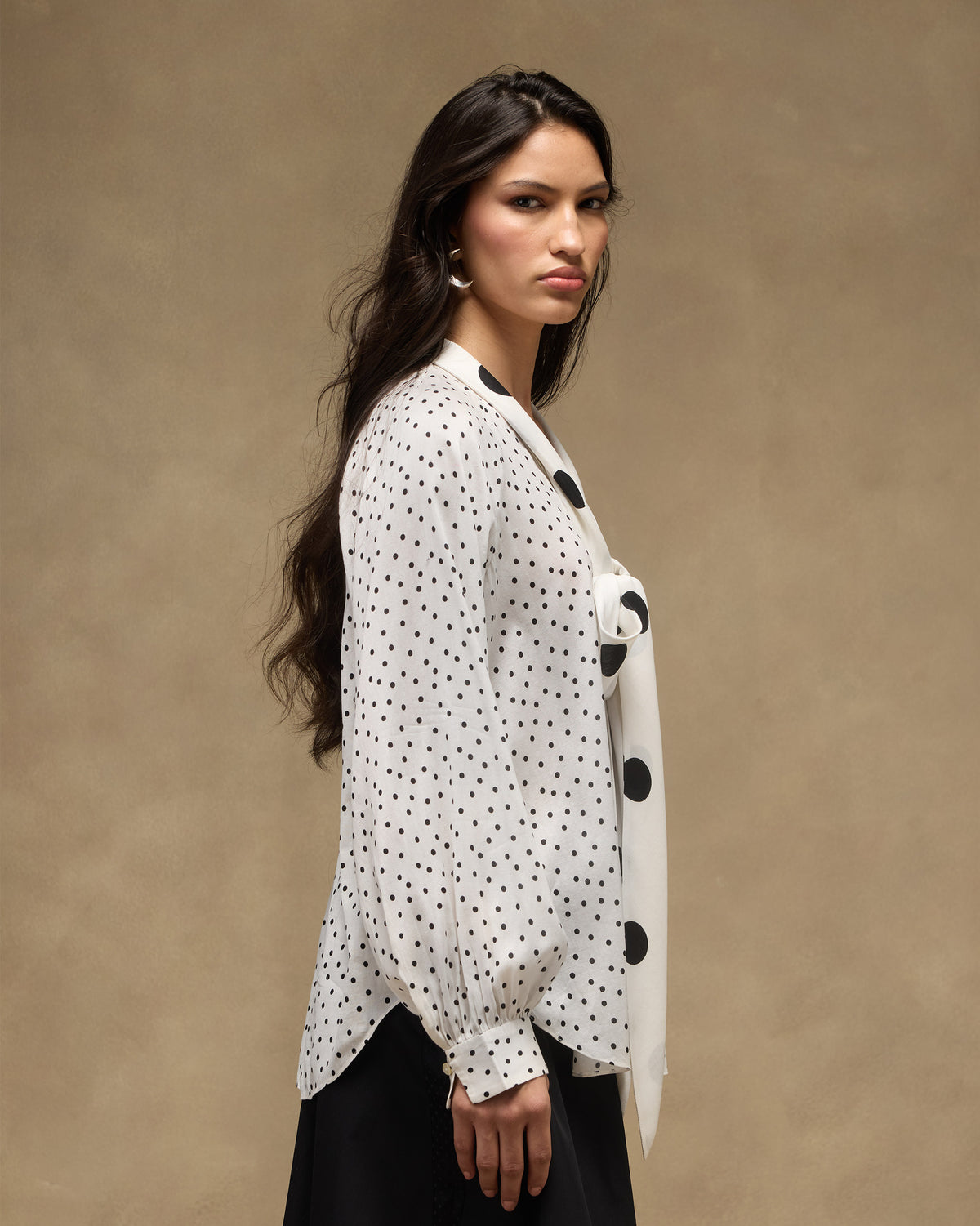 Person wearing an ivory polka-dot Whirl tie-up top with a large-dot bow.