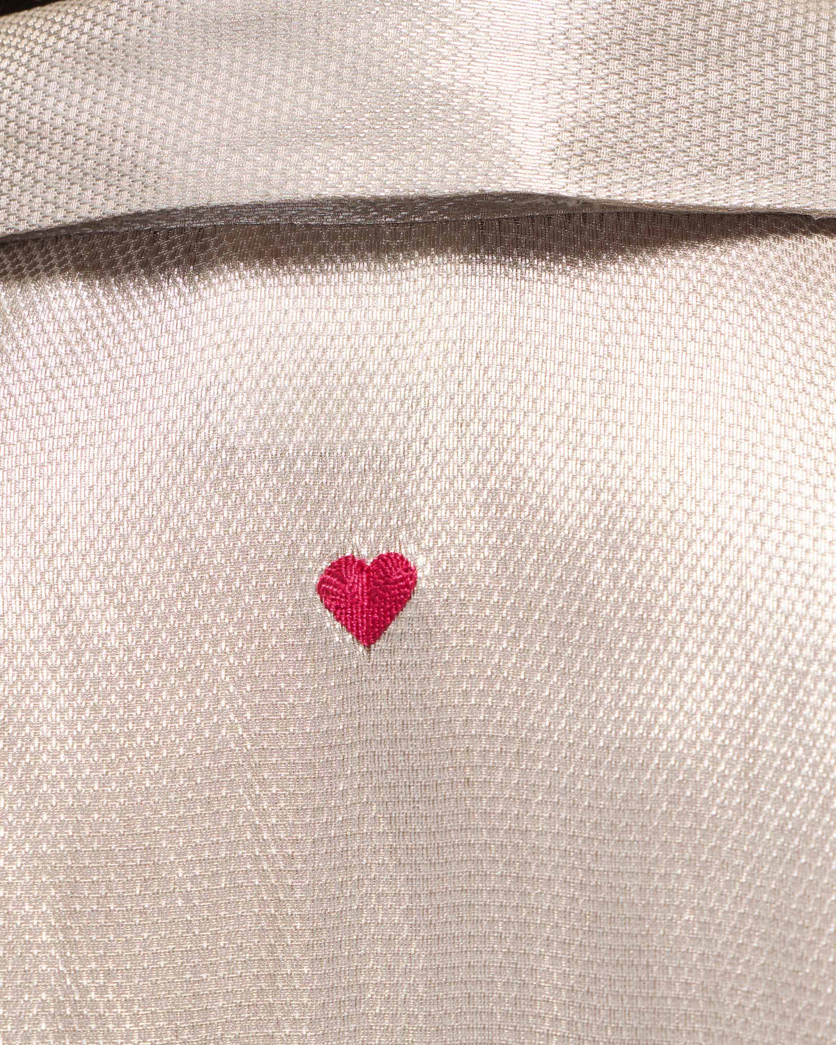 Close-up of a silver tissue organza shirt with a pink embroidered heart.