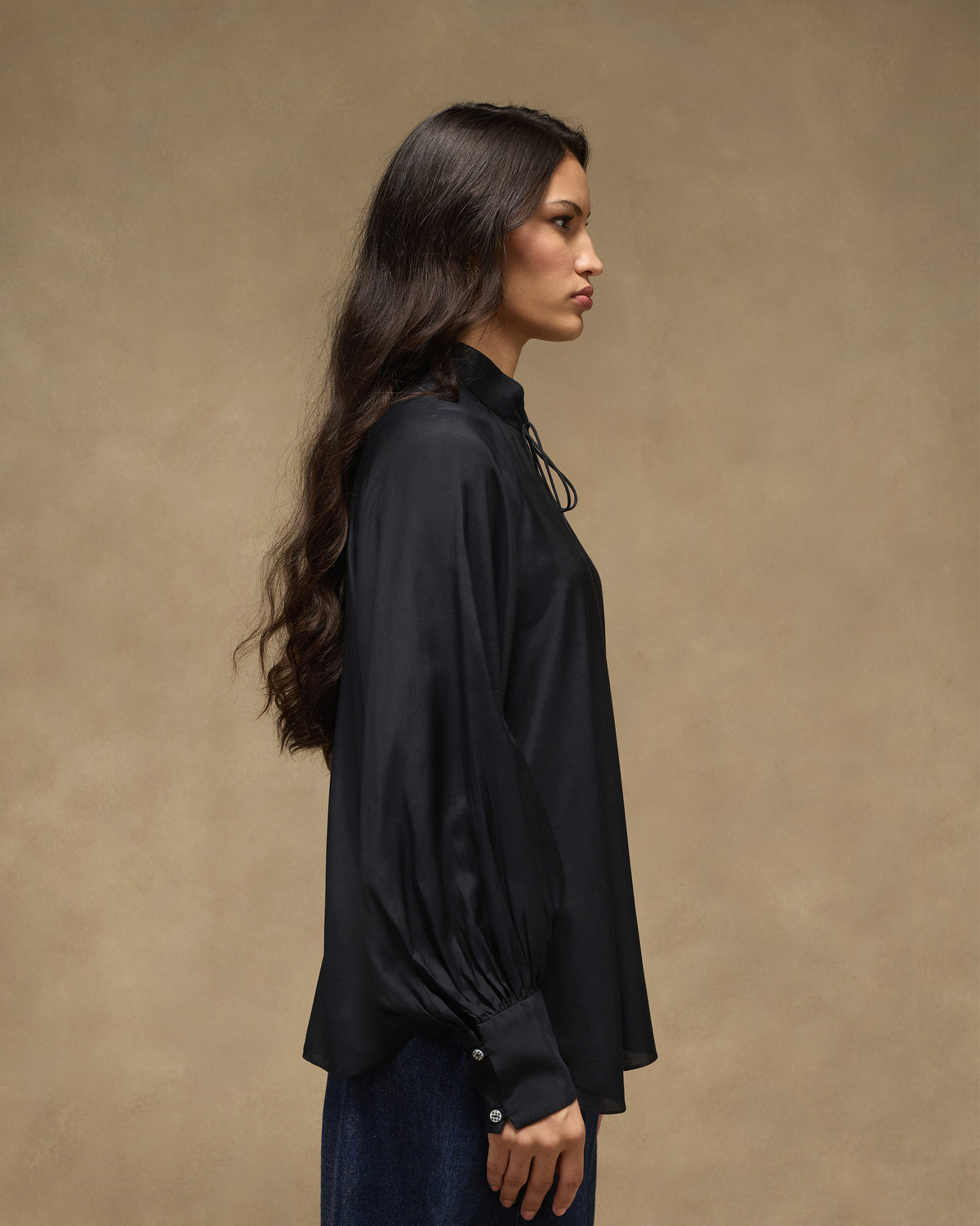 Side view of a black top with voluminous sleeves and wide cuffs.