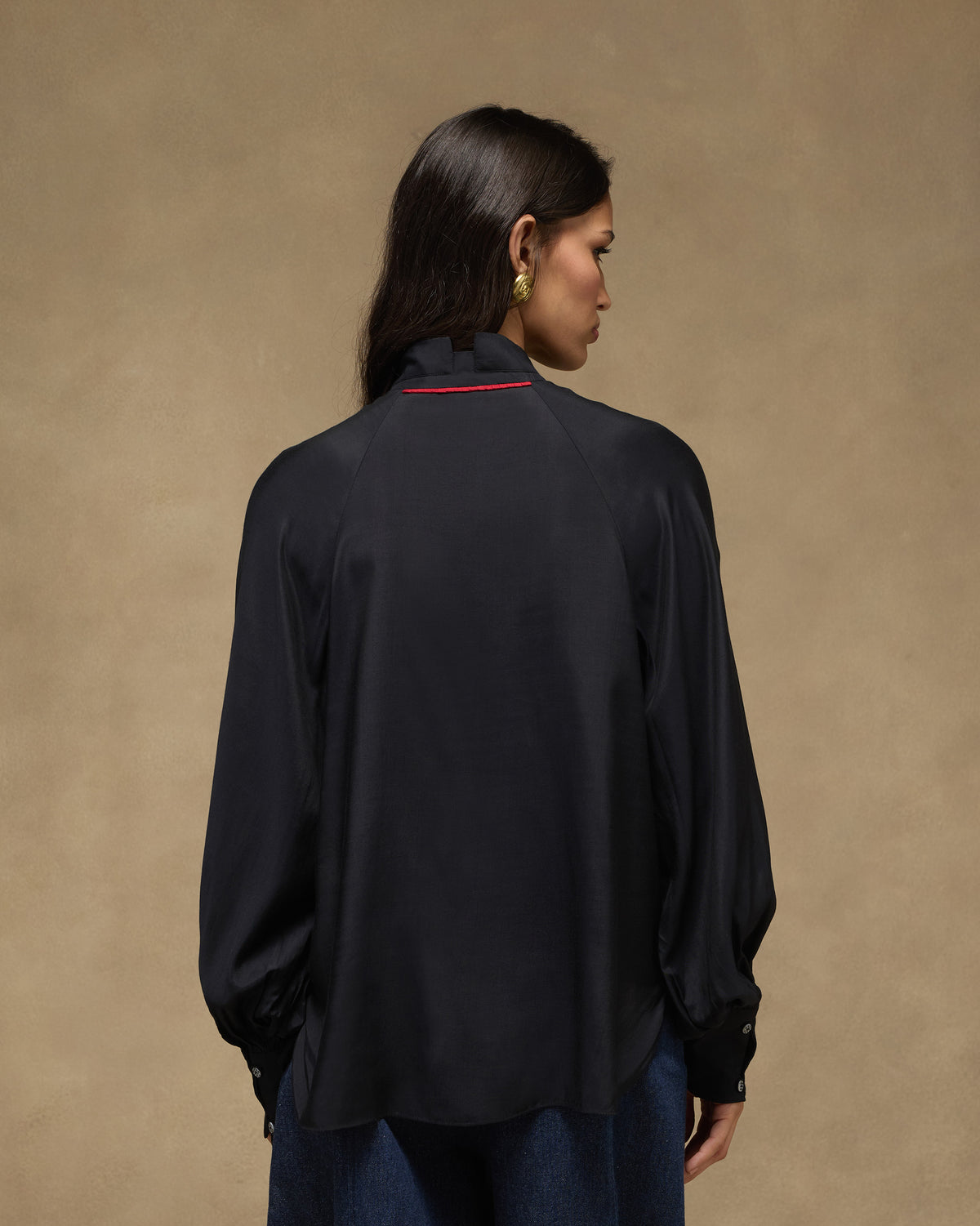 Back of a black high-neck top with red piping at the collar.