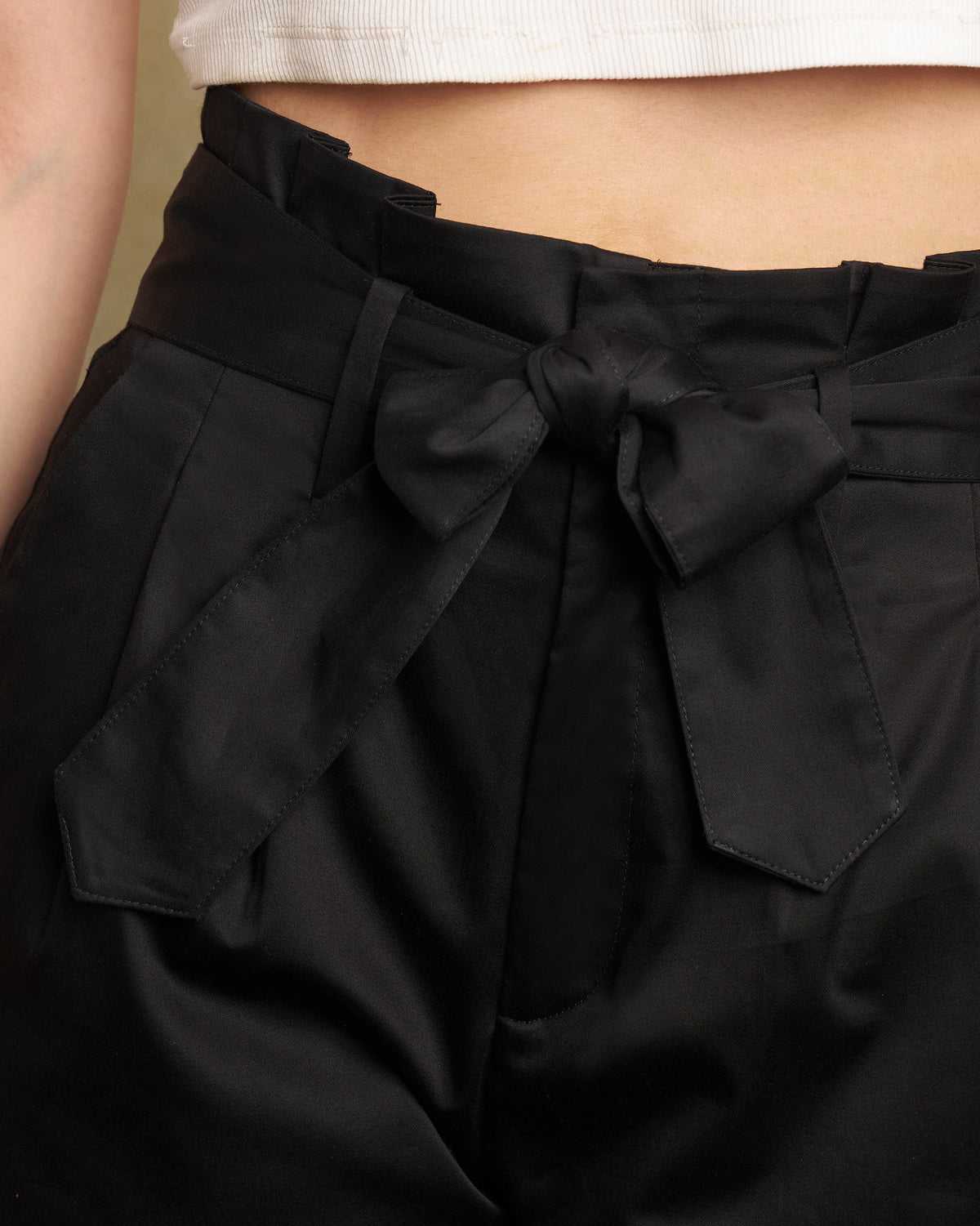 Close-up of black Gumdrop Pants paperbag waist with a tied belt bow.