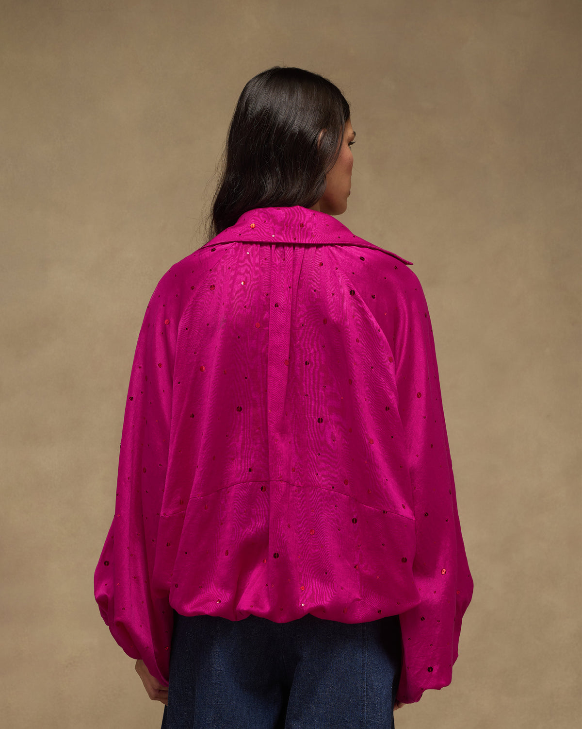 Back of a fuchsia Cloud Overlay with scattered sequins and a blouson hem.