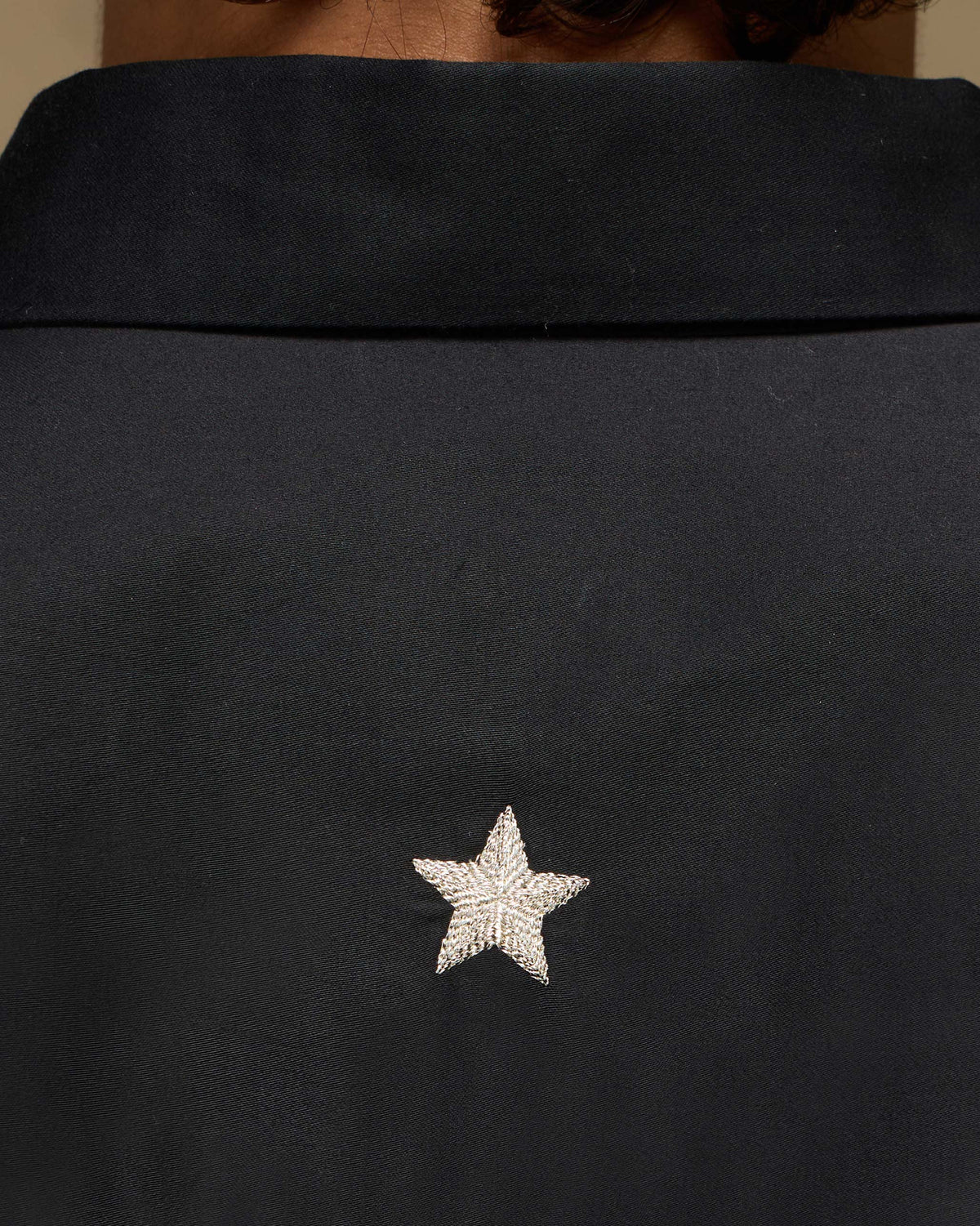 Close-up of a white star on the back of a black Midnight Shirt.
