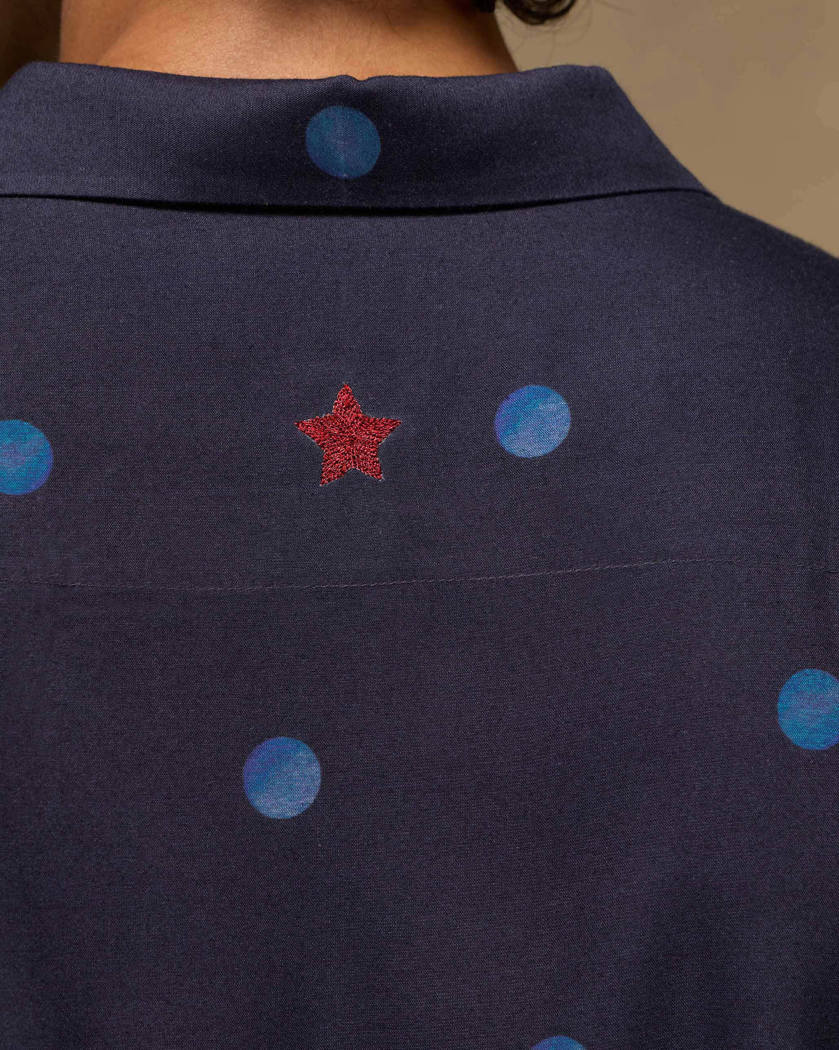 Close-up of the red star on the back of a dark navy Daze shirt.