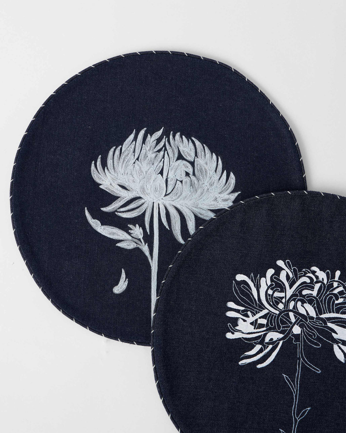 Close-up of Chandramallika placemats showing white flower embroidery and stitched edges.