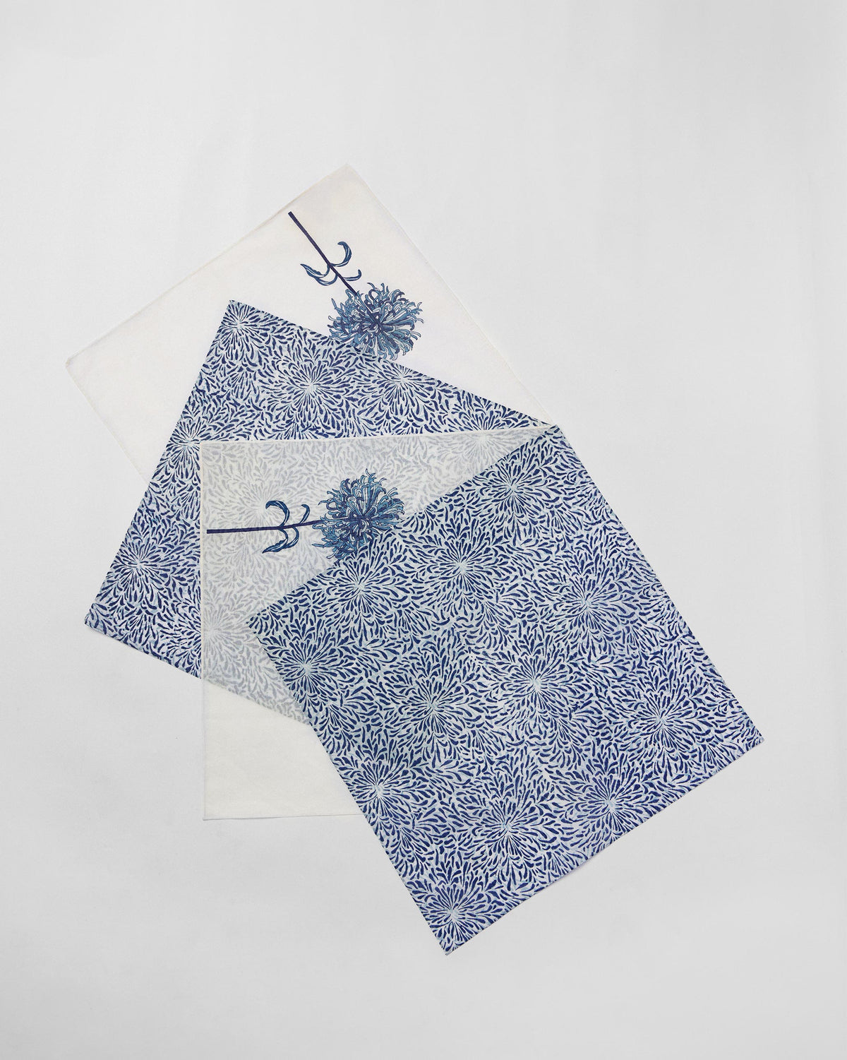 Four Chandramallika Dinner Napkins fanned out in blue and white prints.