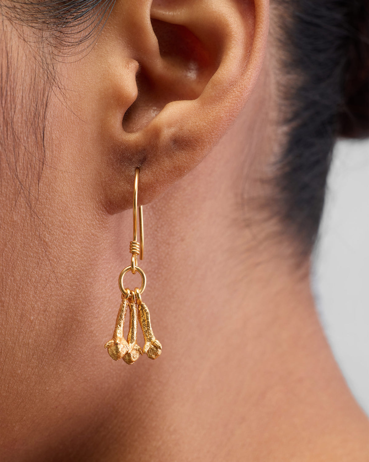Close-up of Clove Earrings worn, with three gold tapered drops below the ear.