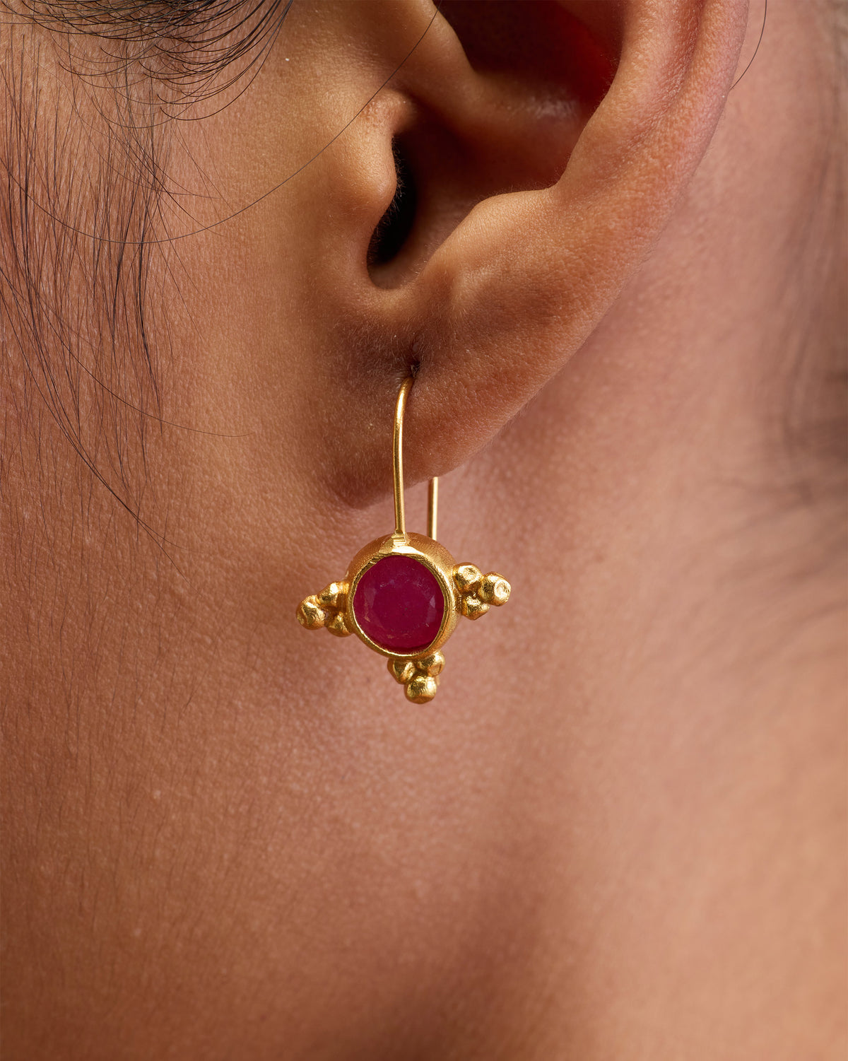 Close-up of Pink Jade Drops worn on an ear, showing a pink stone.