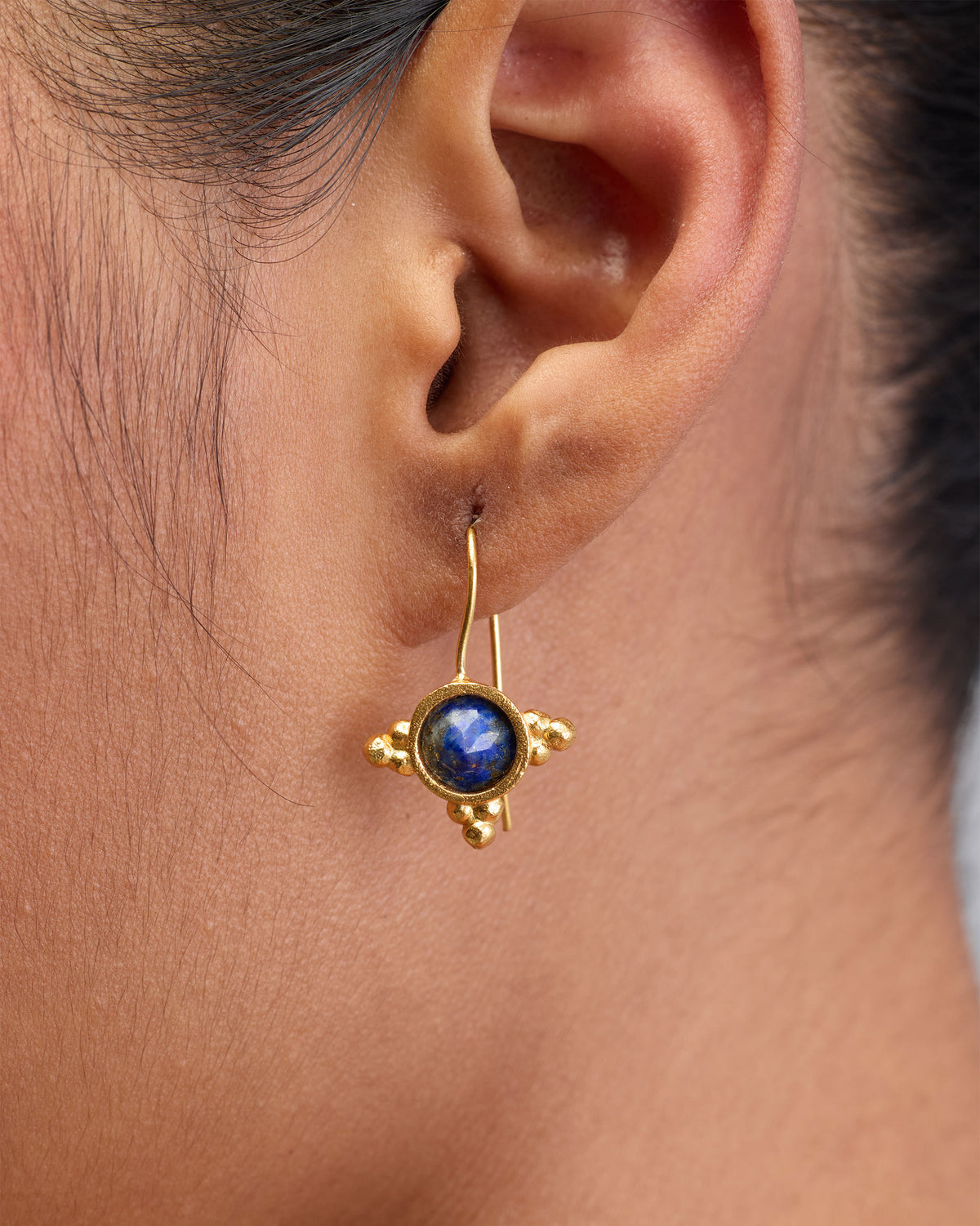 Close-up of Lapis Drops worn on an ear, showing a round blue stone.