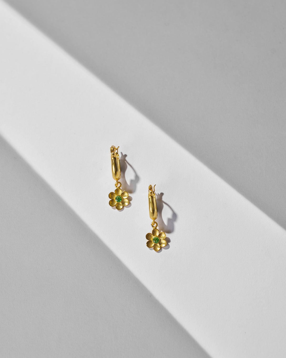 Pair of gold Raat Rani flower hoop earrings laid flat.