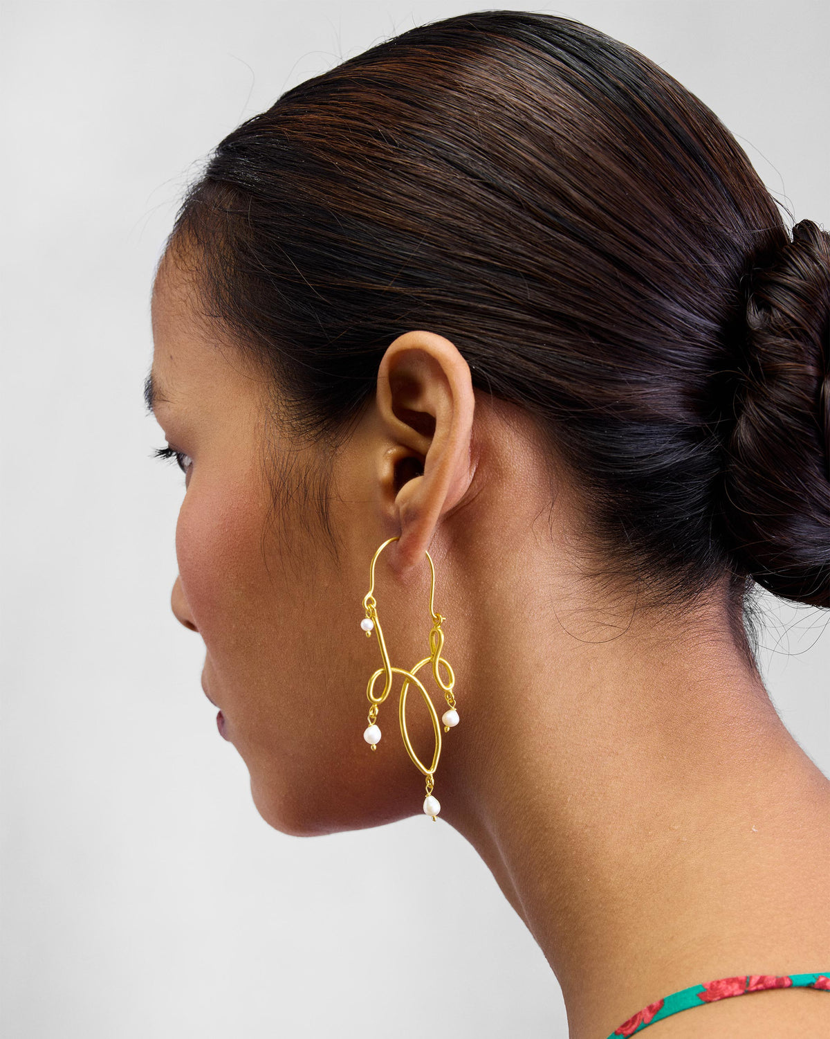 Side profile of a gold Kolam bali with pearl drops.
