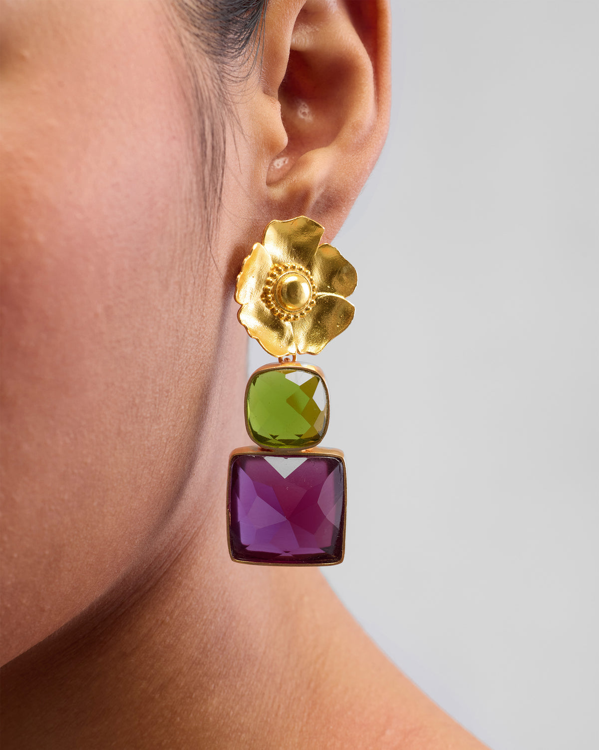 Close-up of a gold dessert rose drop showing green and purple stones.