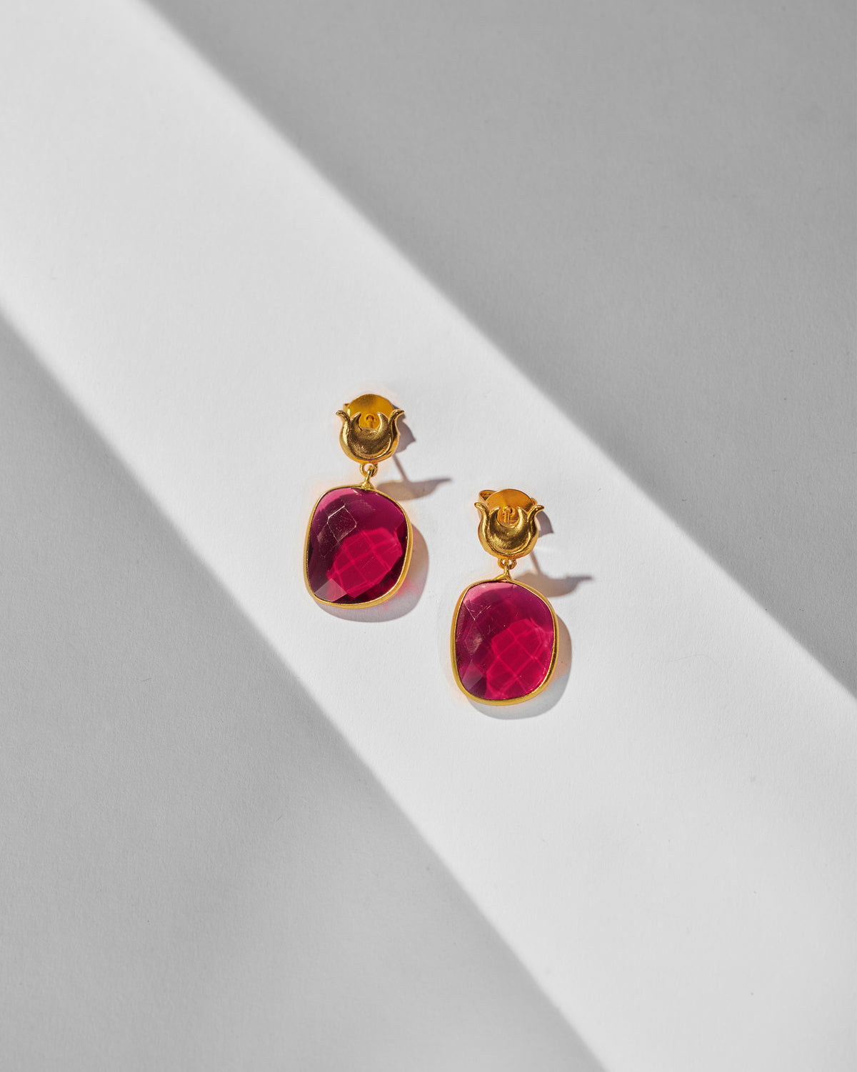 Pair of Chandphool Earrings laid flat, with crescent tops and pink stone drops.
