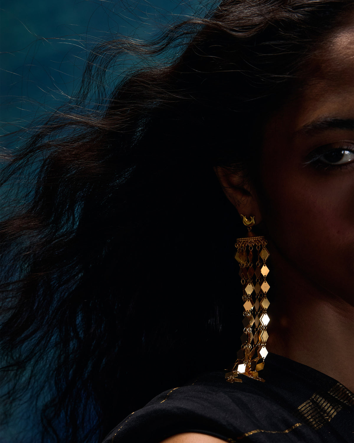 Side profile of long gold Gulbahar earrings with diamond-scale fringe on a person.