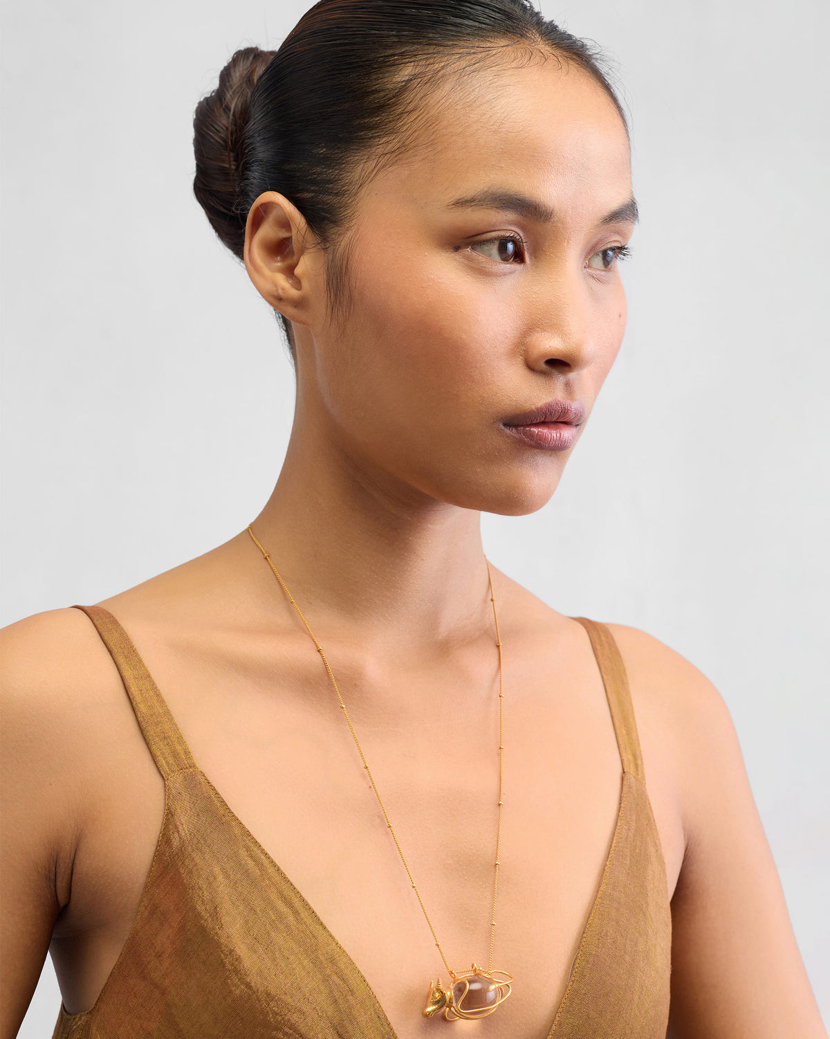 Person wearing a long gold Nandi necklace with a bull pendant at the chest.