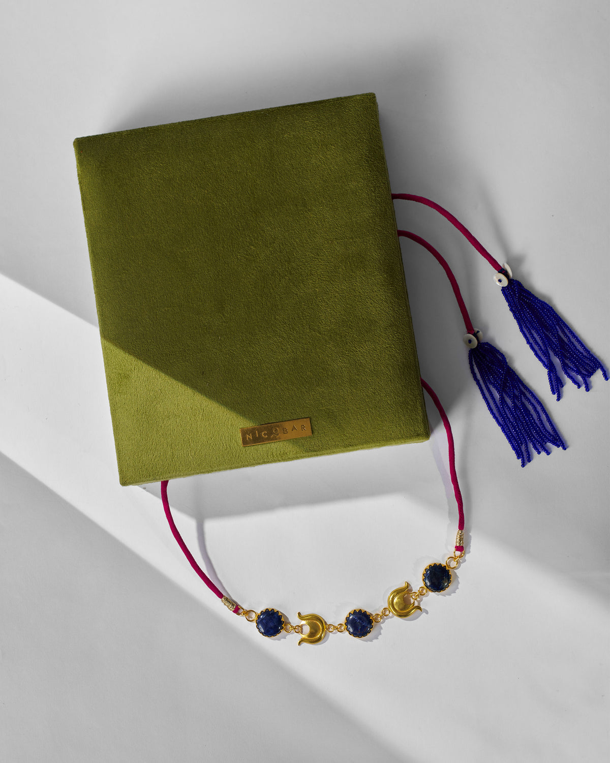 Chandphool Choker on an olive green Nicobar box with blue tassels.