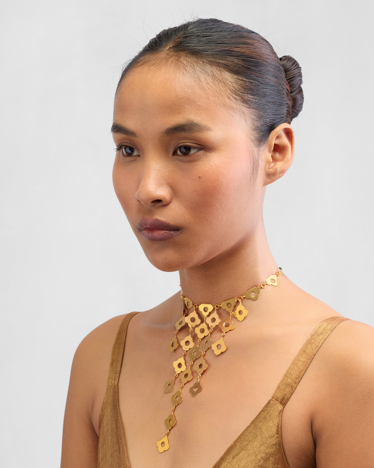 Person wearing a gold Phool Jaal flower-lattice bib necklace.