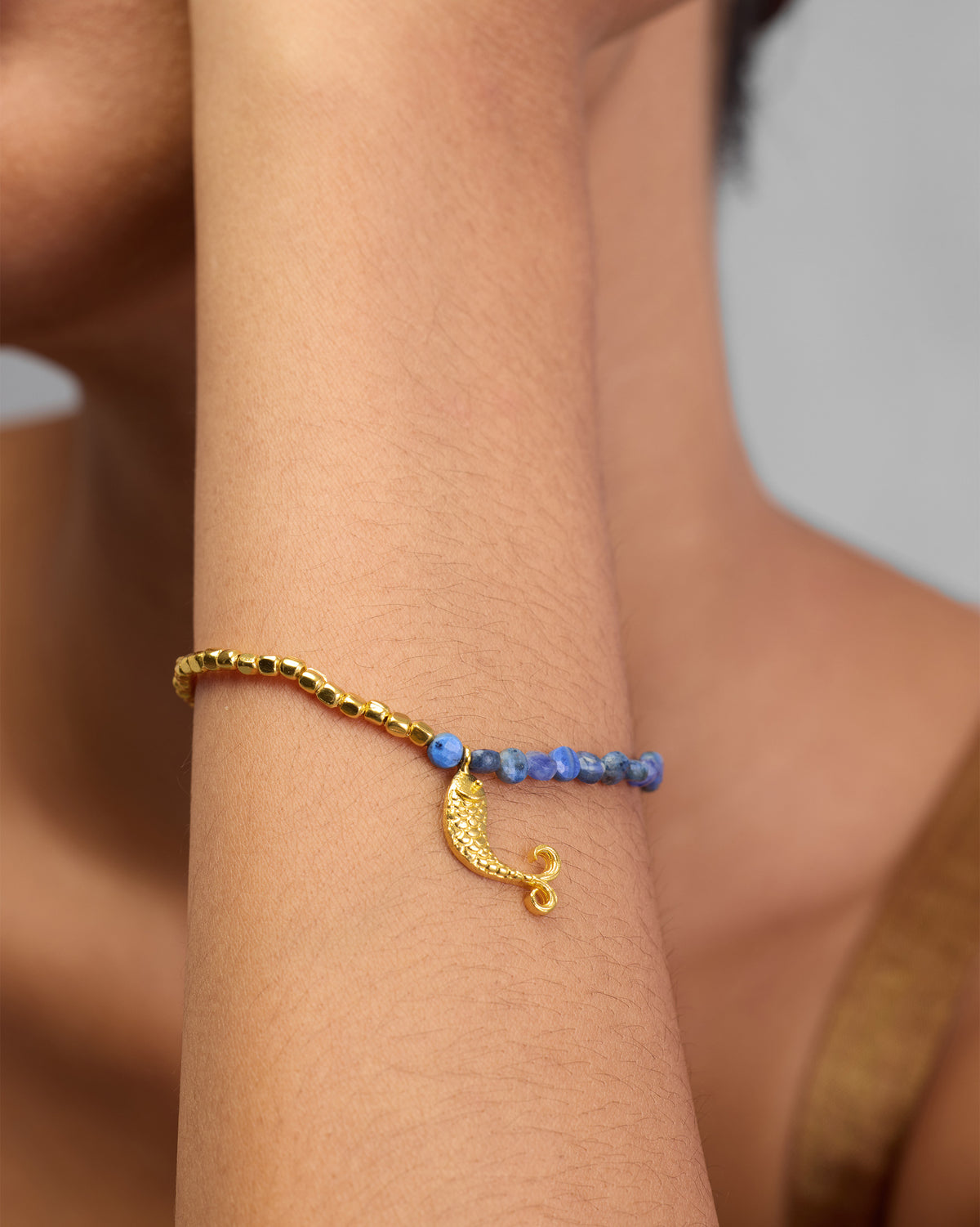 Close-up of a Jalpari Bracelet on a forearm, showing its curved gold charm.
