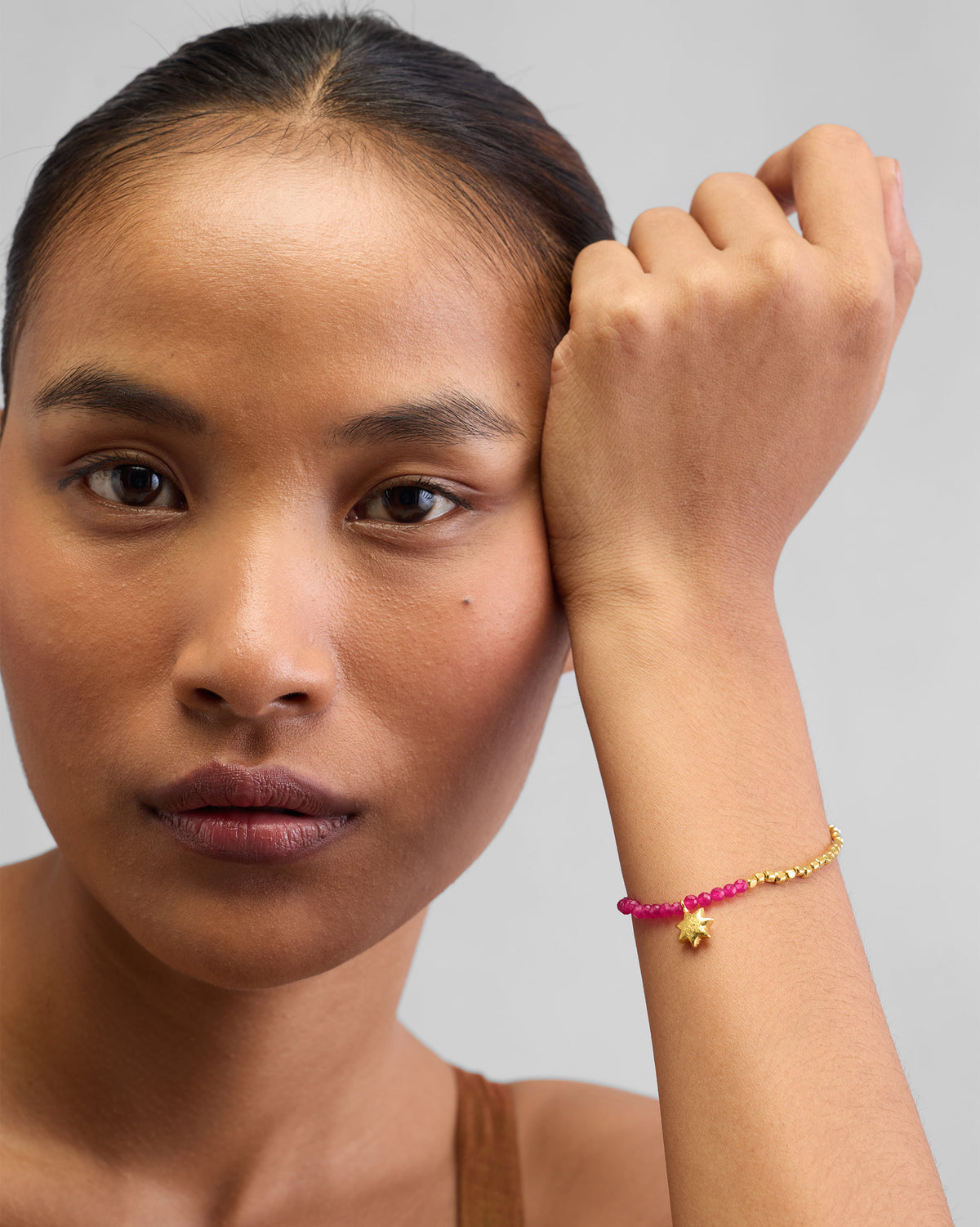 Person wearing a Sitara Bracelet with the wrist resting near the face.