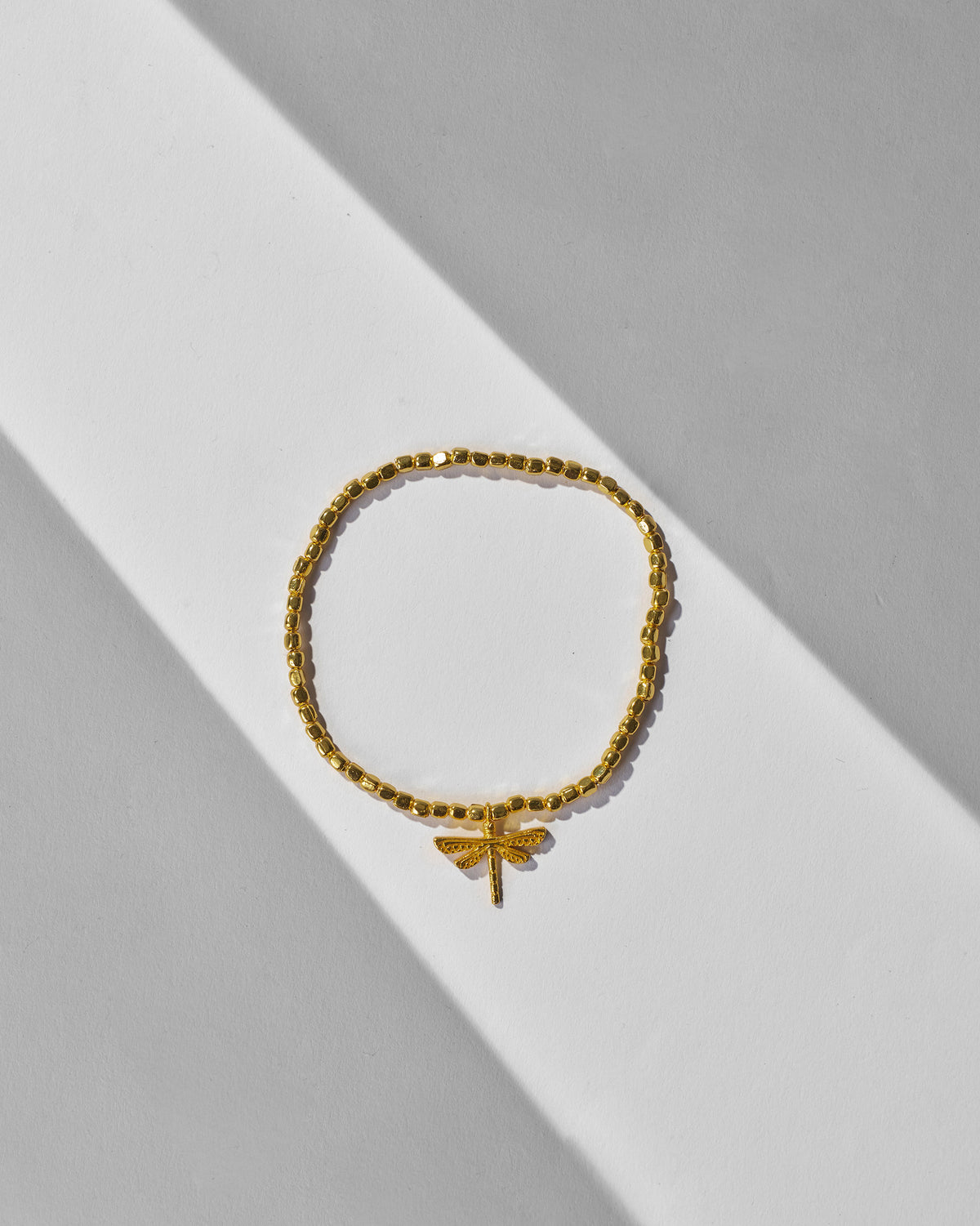 Gold beaded Dragonfly Bracelet laid flat with its dragonfly charm.