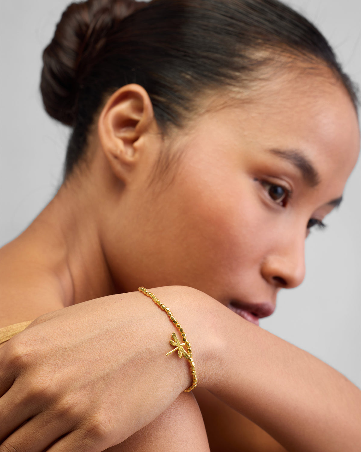 Person wearing a gold Dragonfly Bracelet on the wrist.