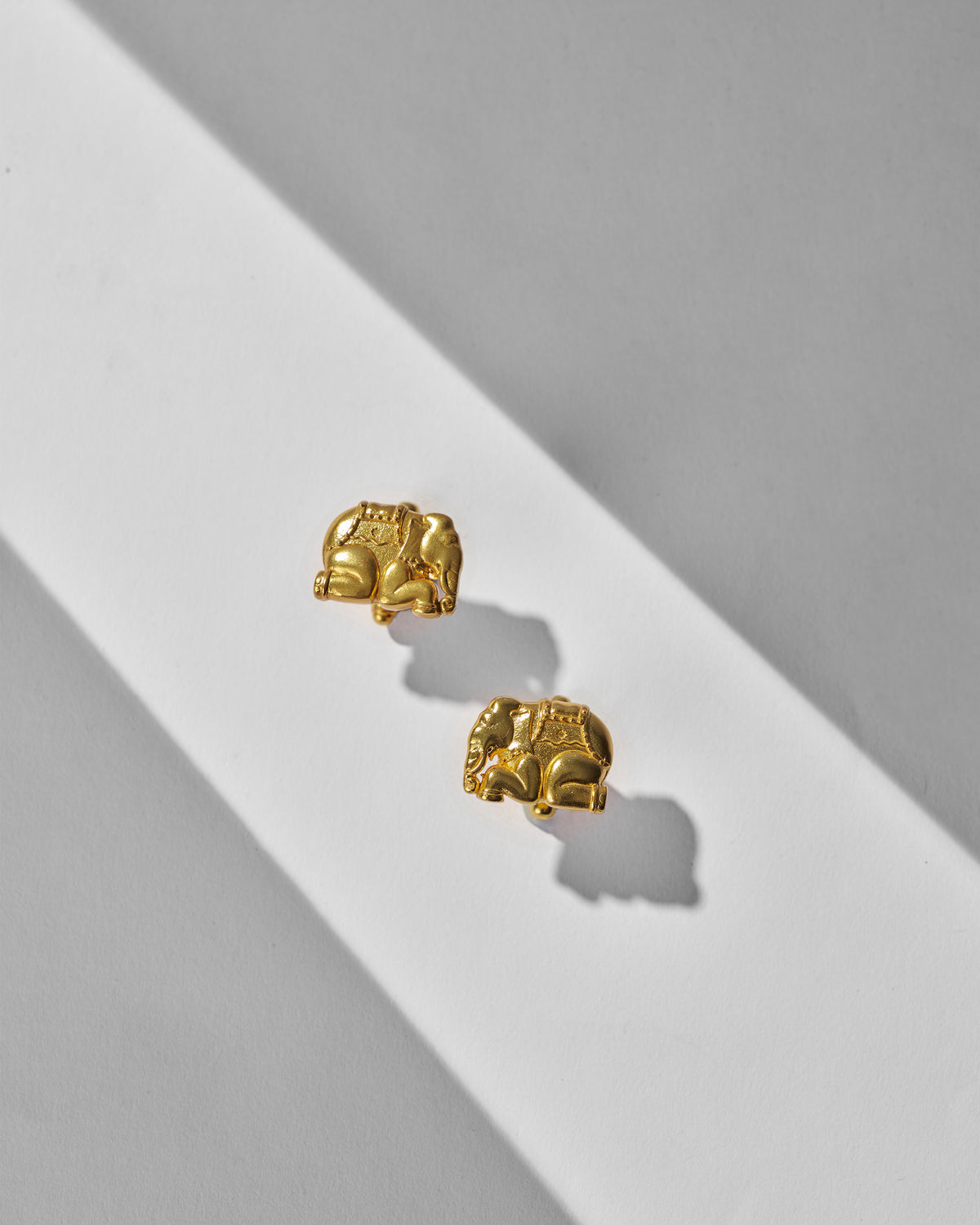 Pair of Appu Cufflinks laid flat, each with a gold elephant motif.