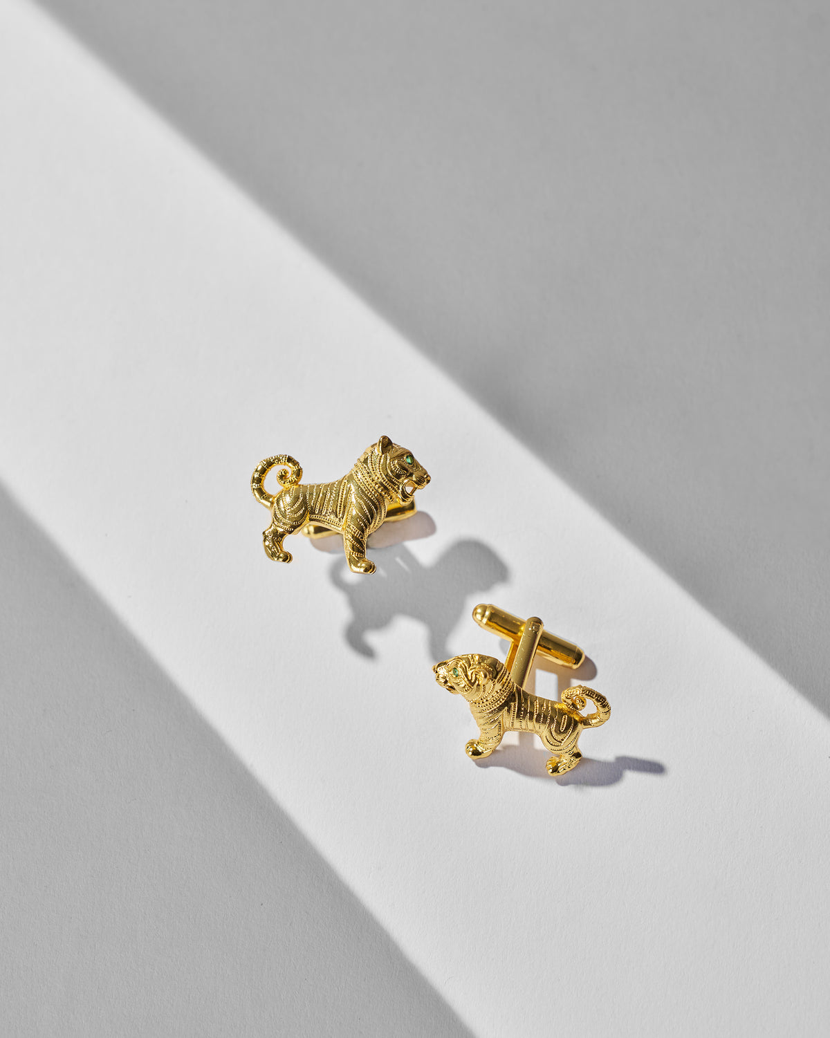 Pair of Roar Cufflinks laid flat with gold tiger motifs.