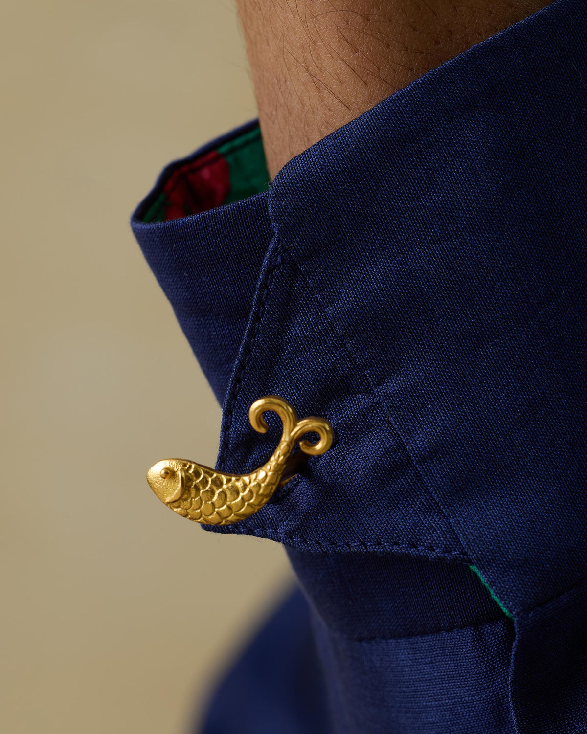 Close-up of a gold Jalpari fish motif on a navy shirt collar.