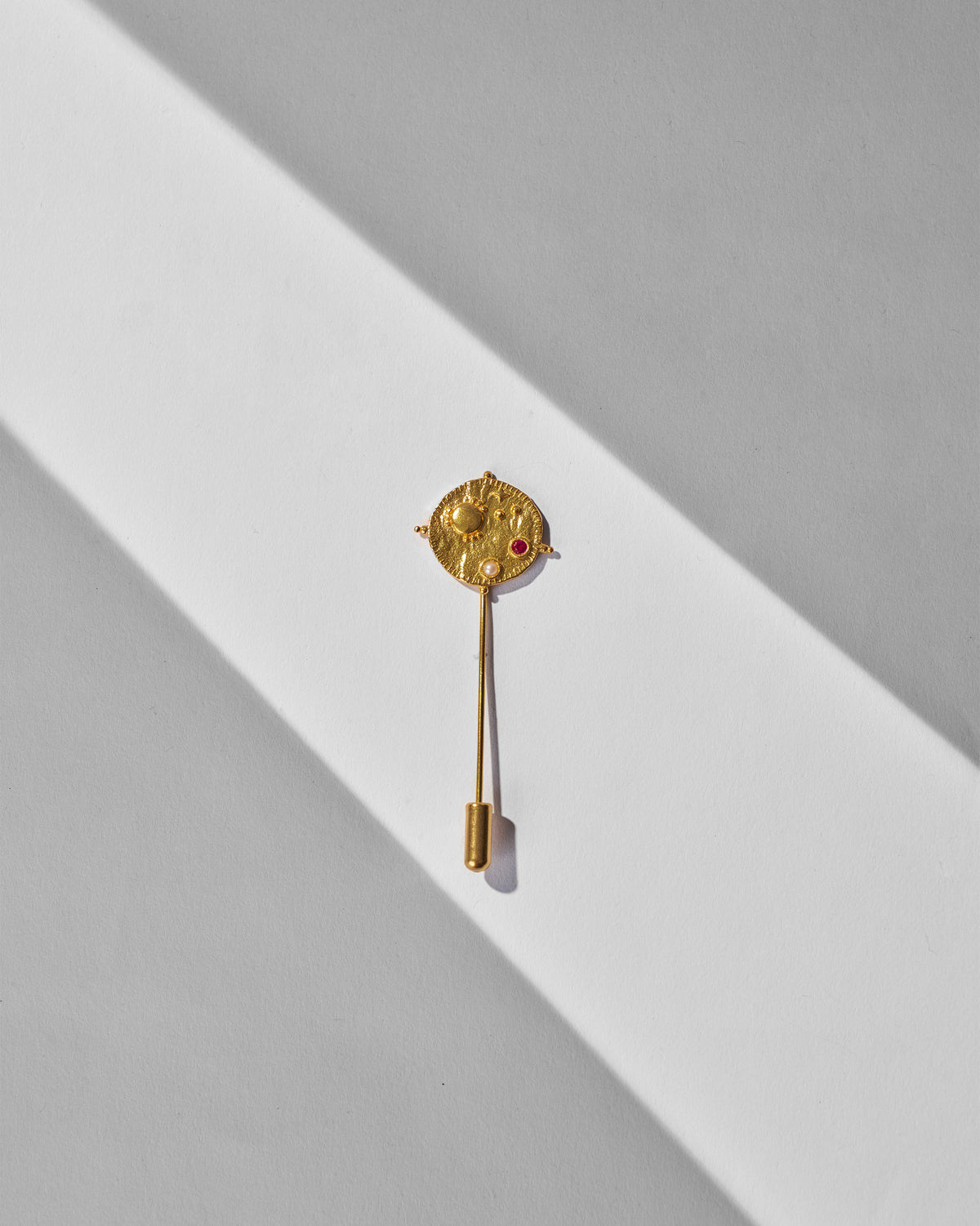 Nebra Lapel Pin laid flat showing its round gold head and stem.