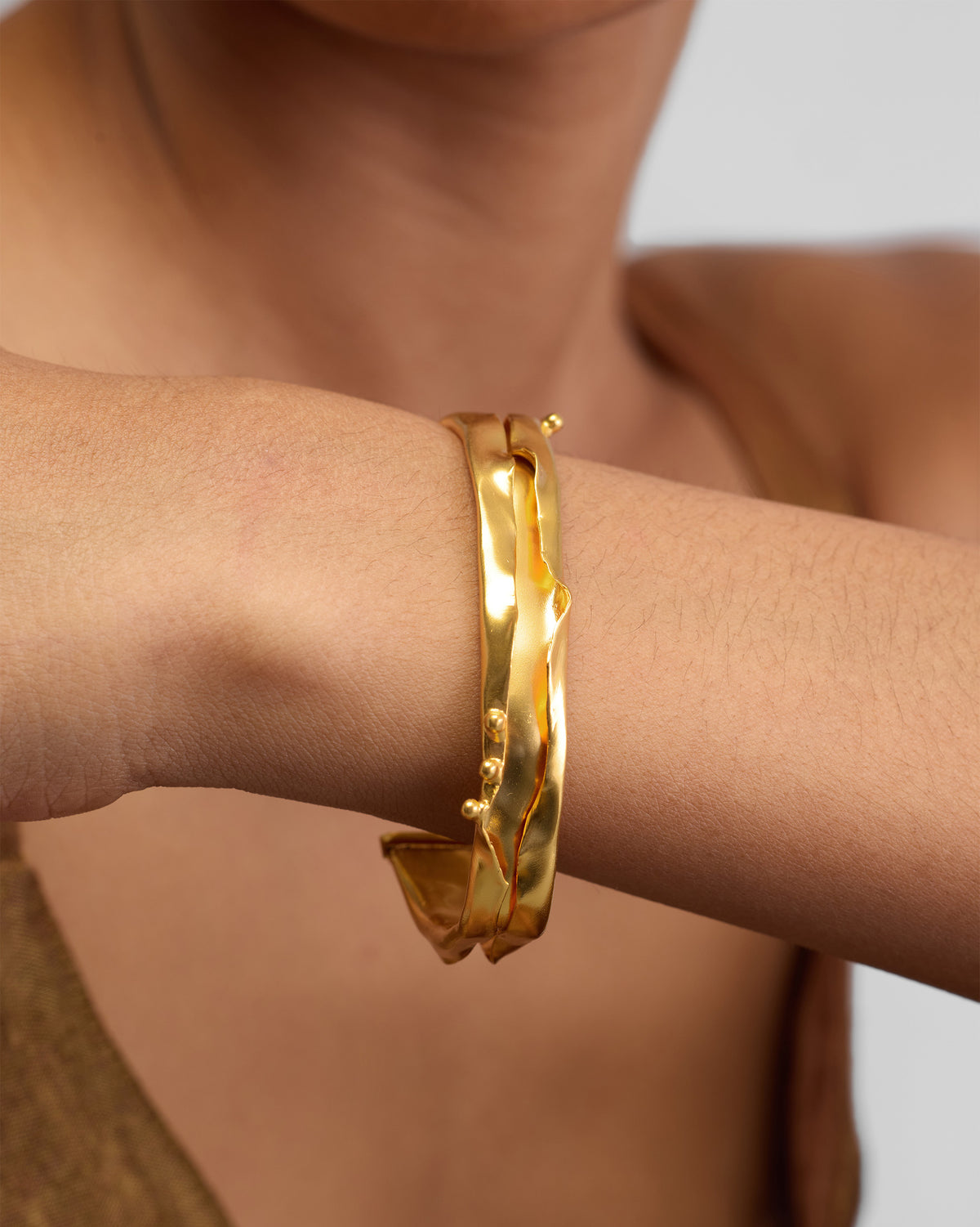 Close-up of a gold Dhaara cuff on a wrist showing its wavy surface.