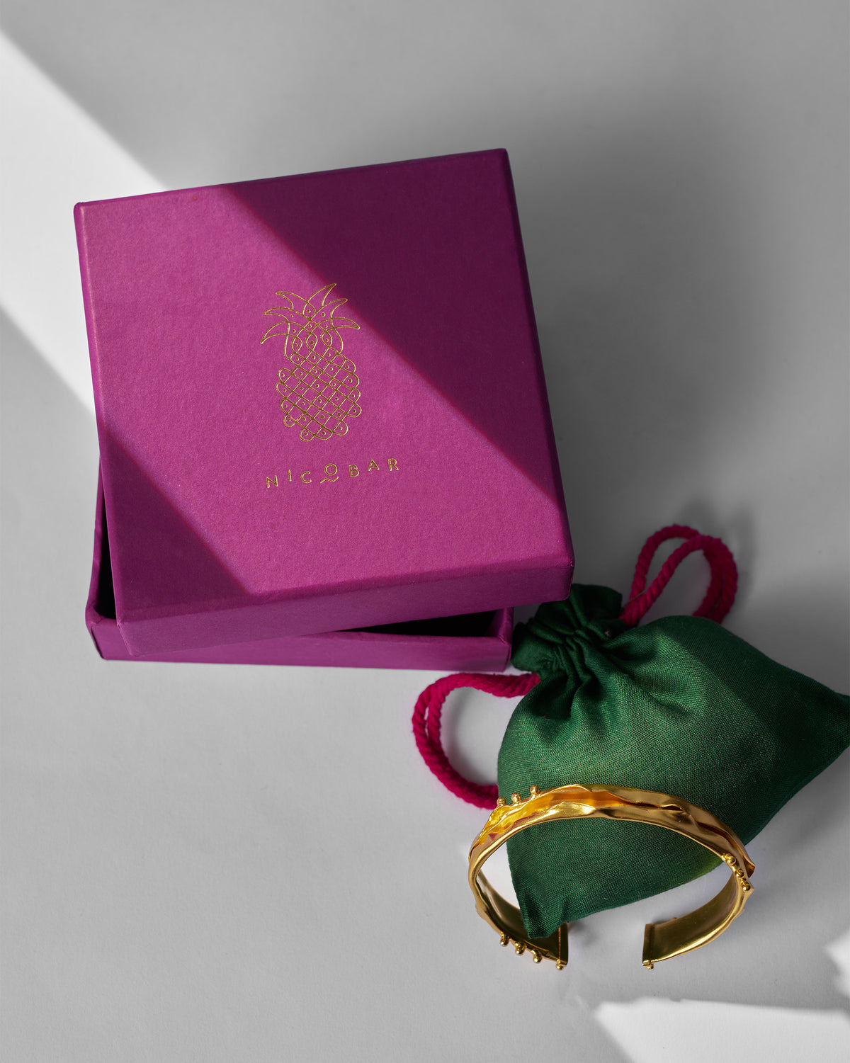 Dhaara cuff beside a magenta gift box and green pouch.