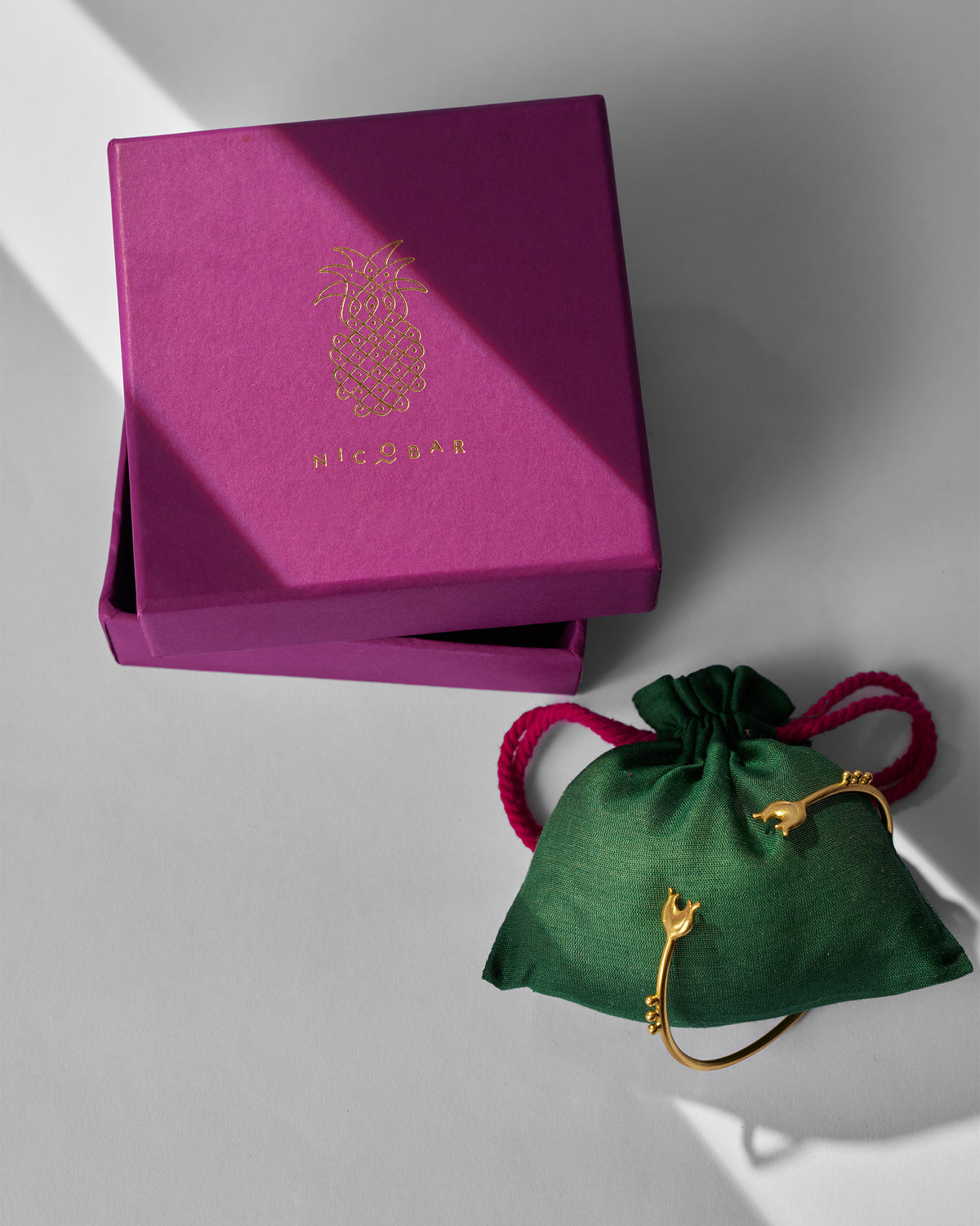 Chaandphool Cuff resting on a green pouch beside a magenta gift box.