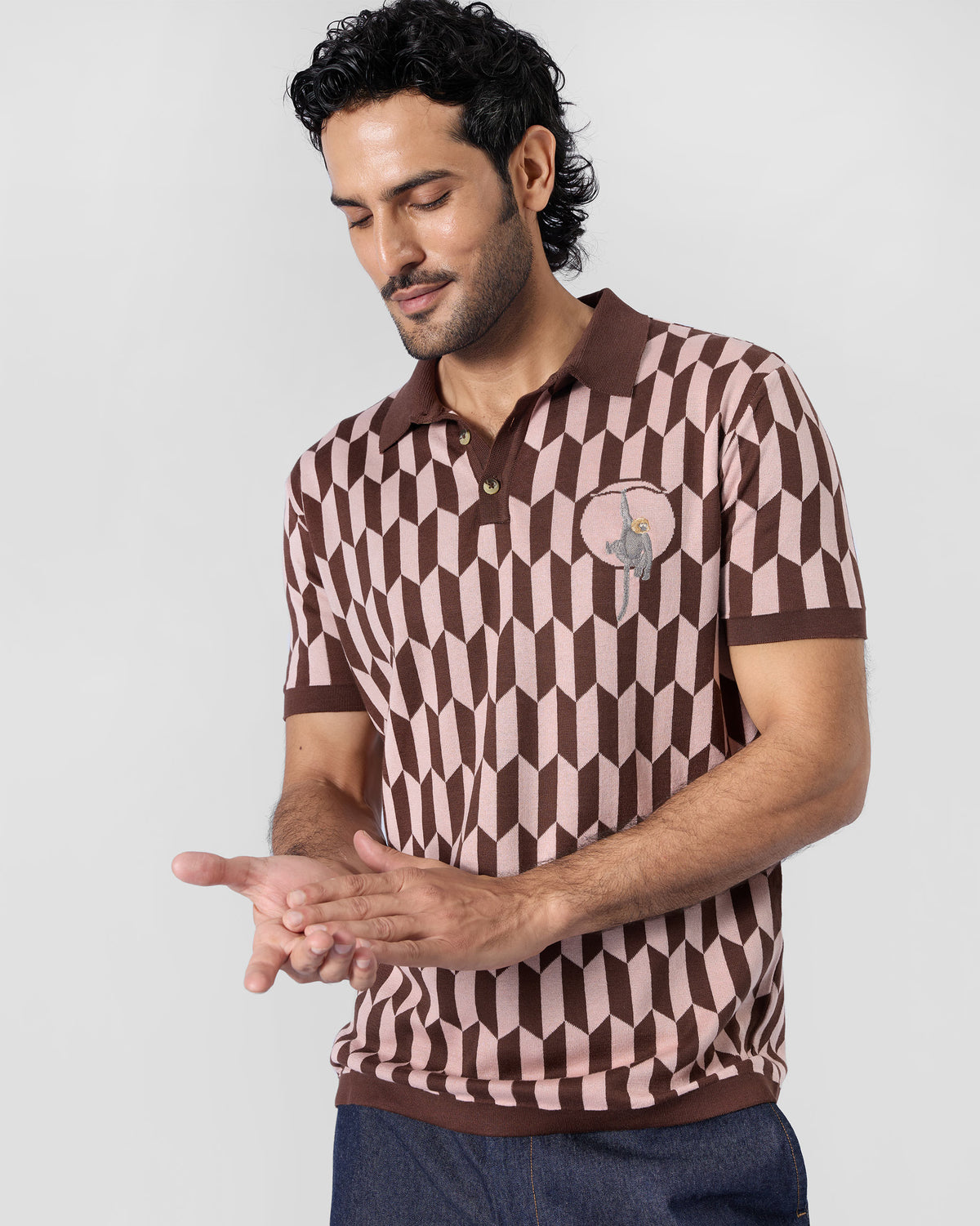 Person wearing a brown-and-pink Langur polo with a monkey chest motif.