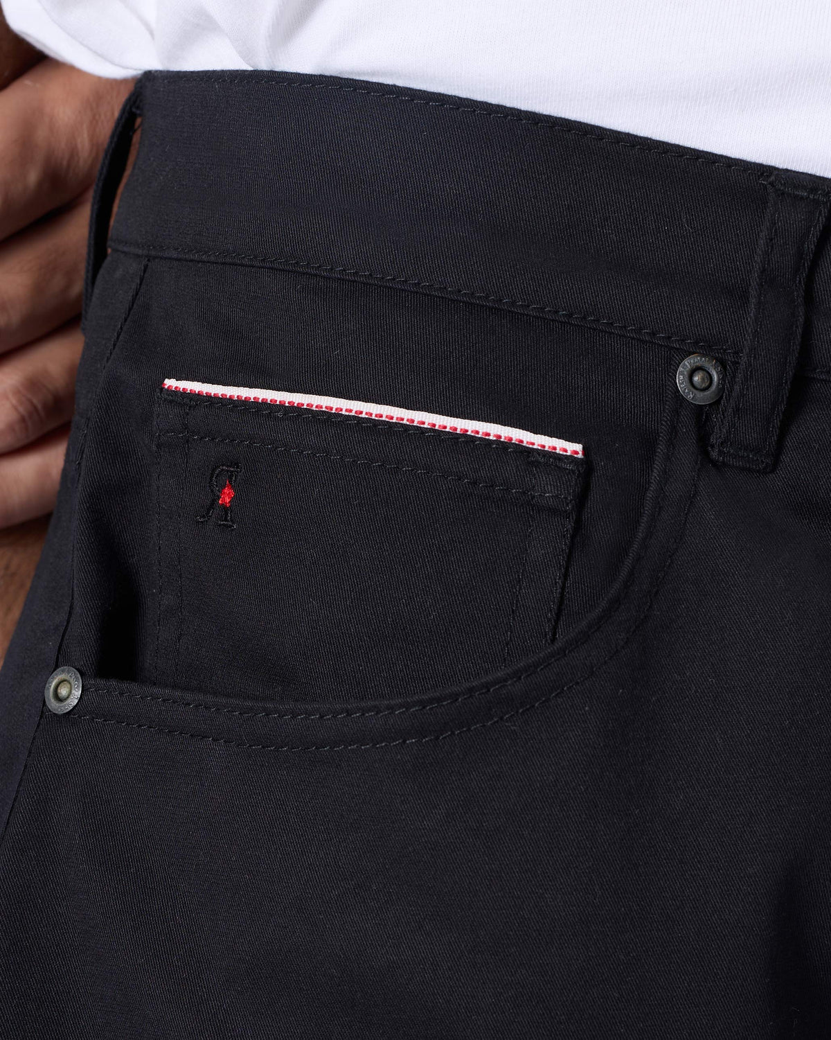 Close-up of a black Serow jodhpur pant pocket with red accent detail.
