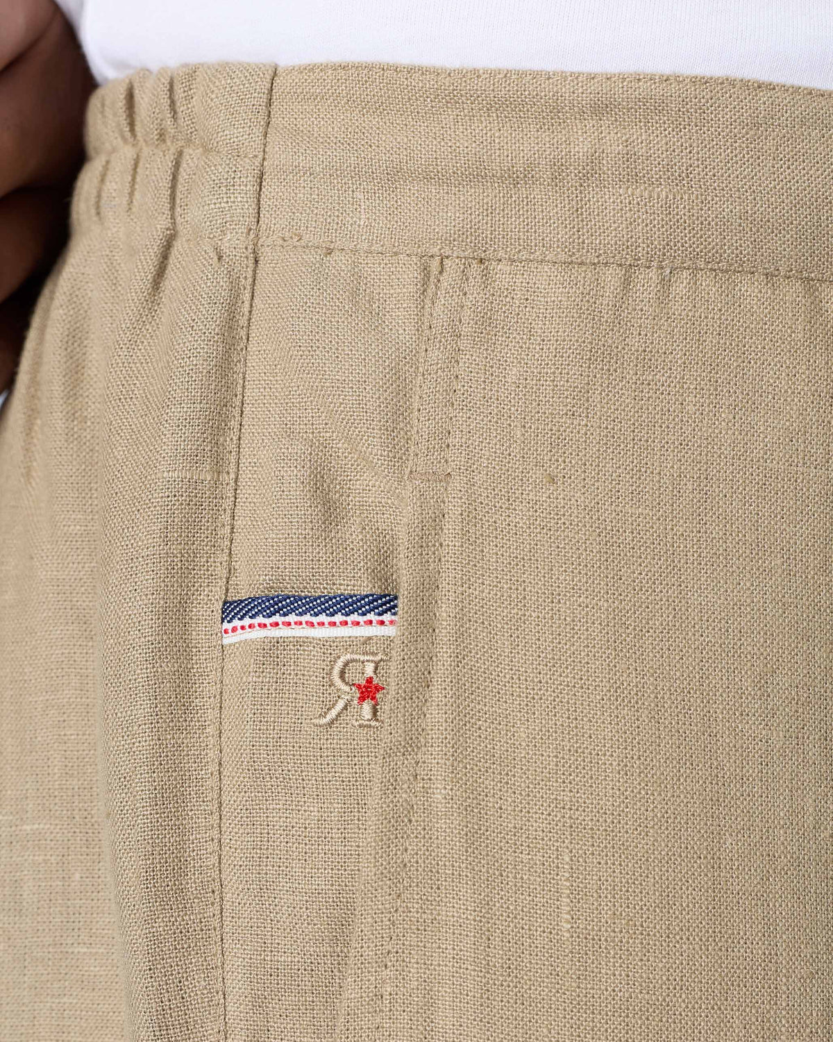 Close-up of sand Ibex trousers showing the side pocket trim and red star mark.