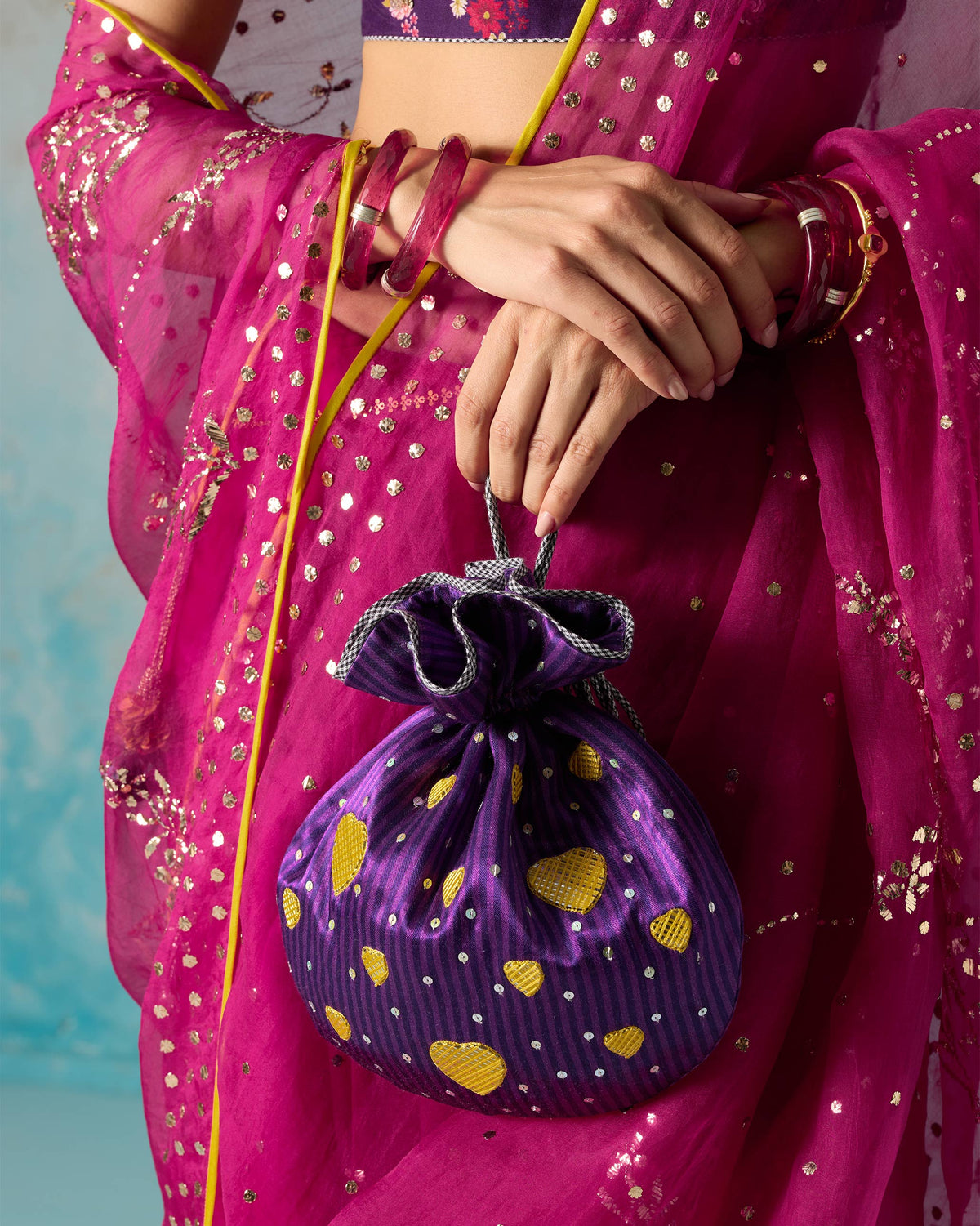 Person holding a violet Meher Potli with gold heart motifs and sequins.