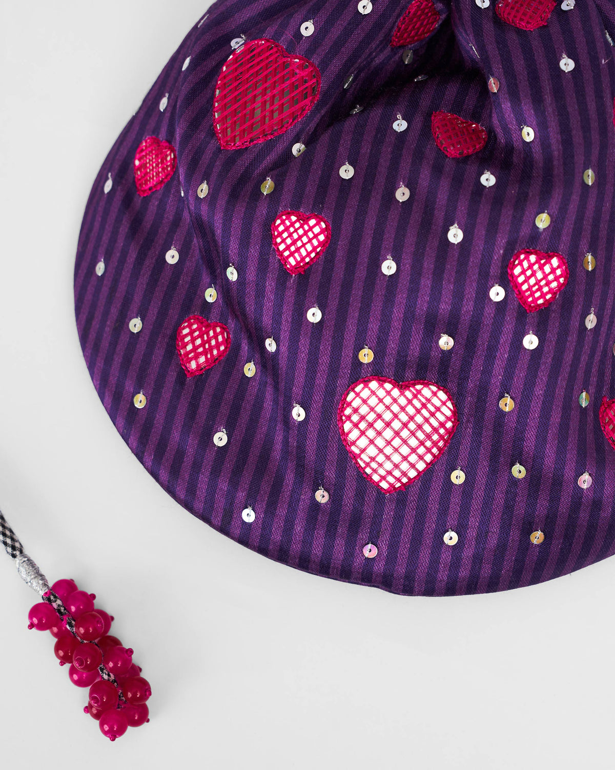 Close-up of the Meher Potli showing pink heart motifs and sequins on violet stripes.