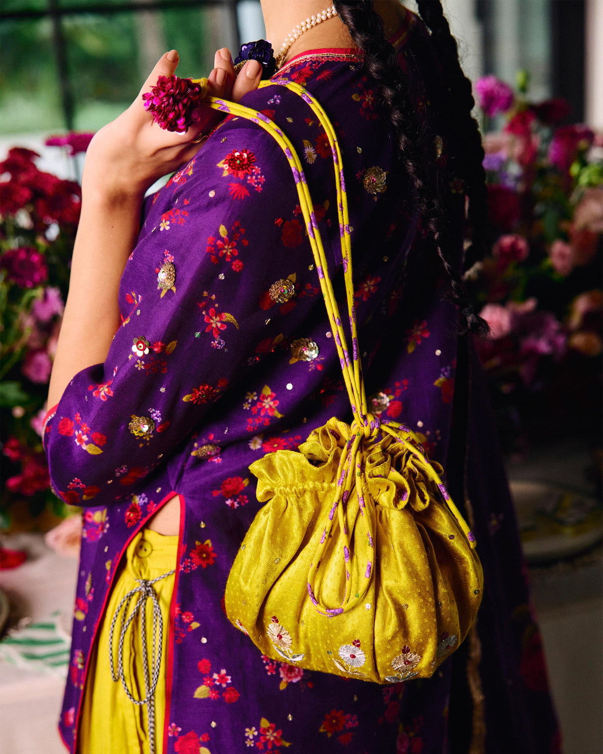 Person holding a chartreuse Firefly Potli with embroidered flower motifs.