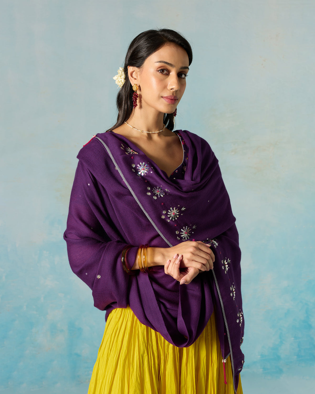 Person draped in a violet Bahaar shawl with embroidered flowers down one side.
