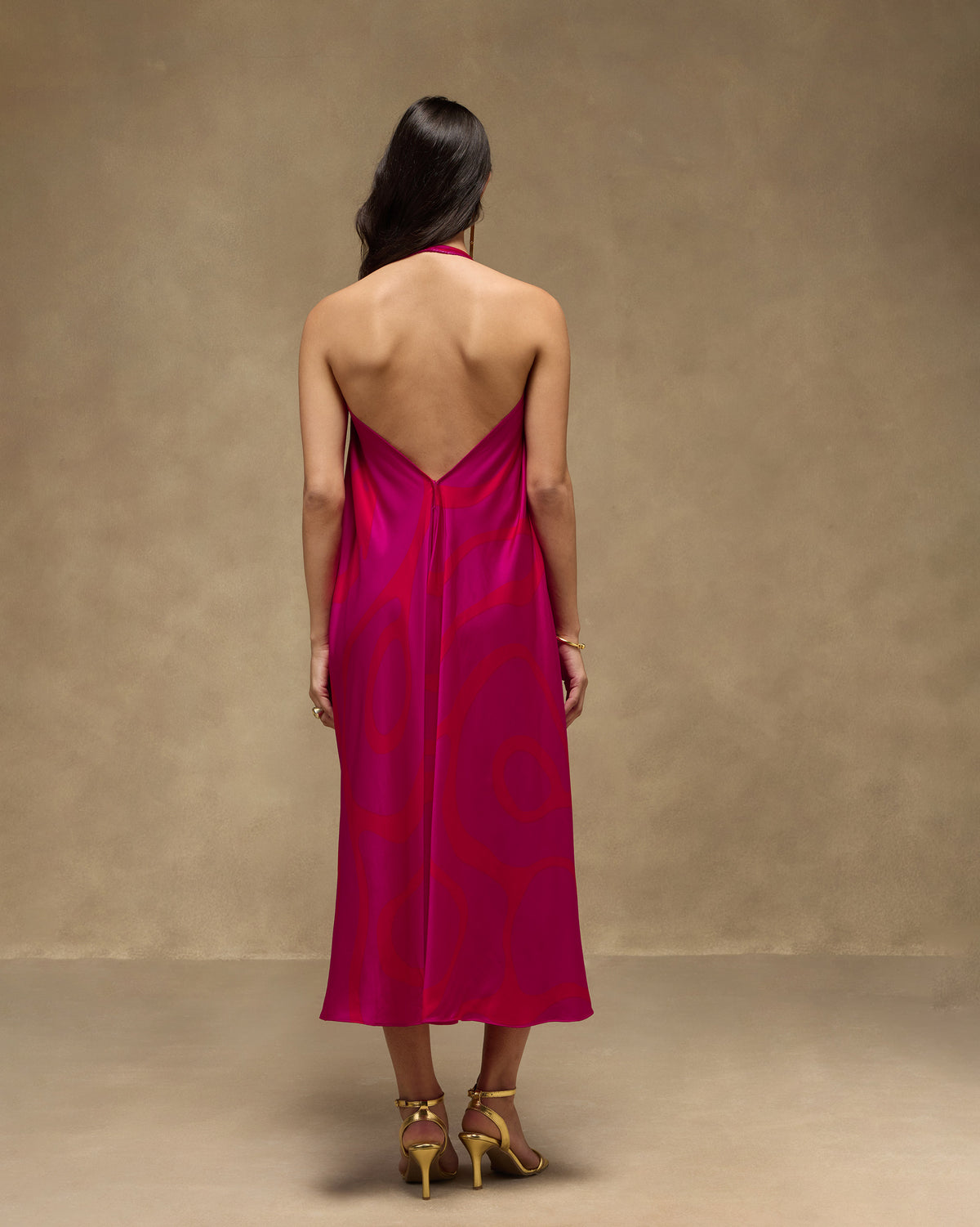 Back of a pink and red Shaker Halter Dress with an open back worn by a person.