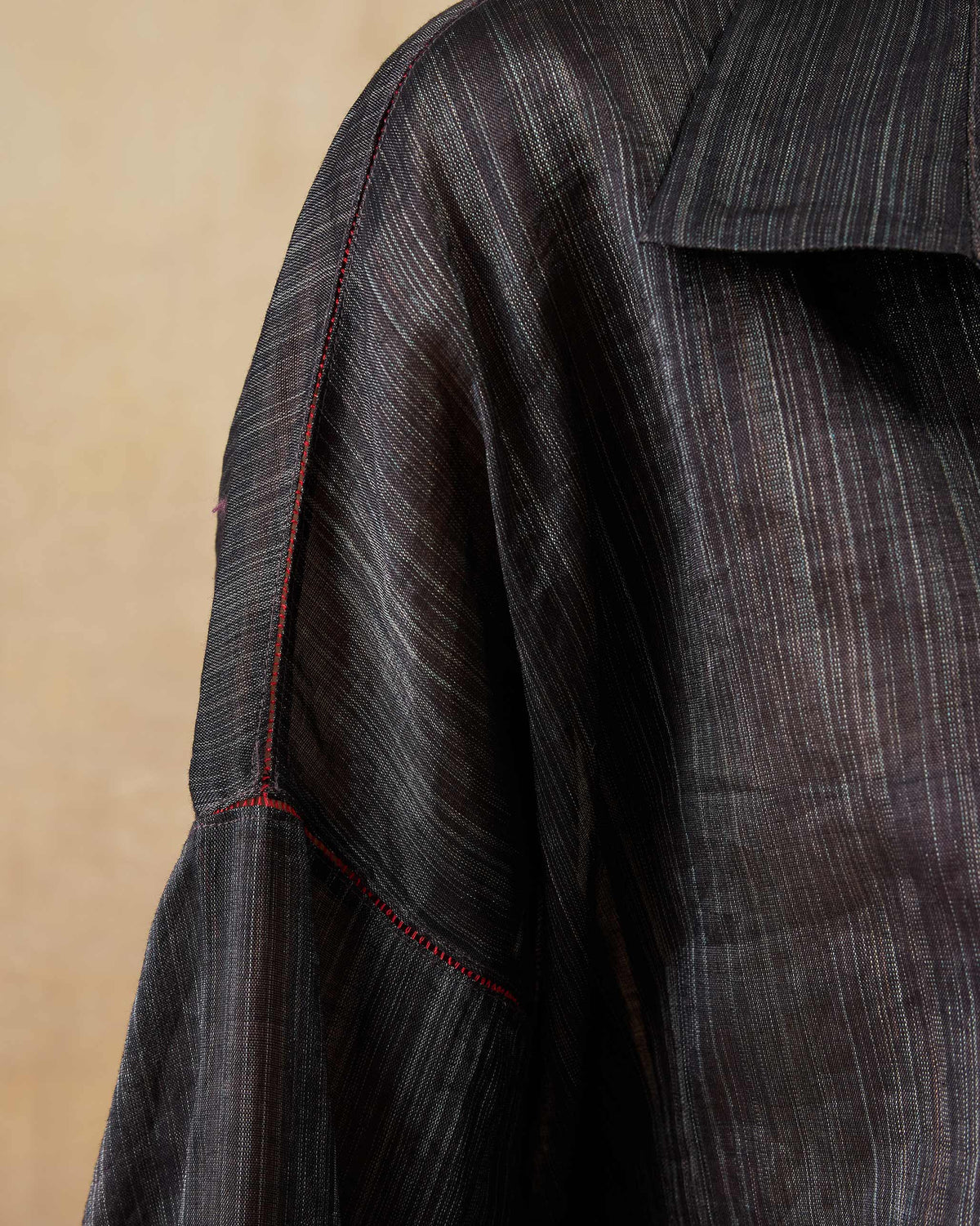 Close-up of red fagotting on the sleeve of a black Firefly shirt.