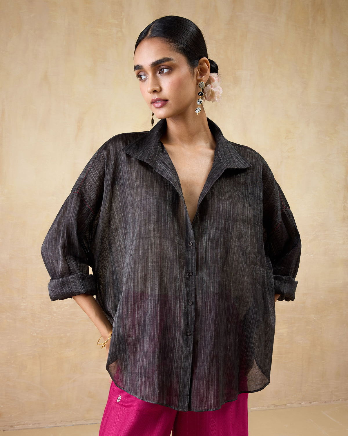 Person wearing a black Firefly shirt with an open collar and sheer metallic fabric.