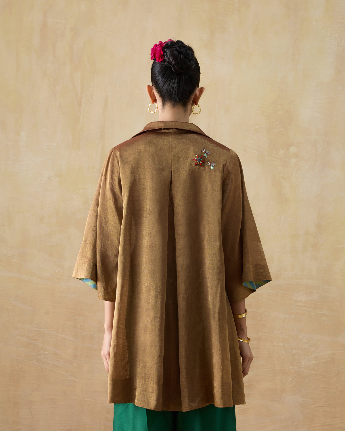 Back of a metallic gold A-line shirt with a box pleat.