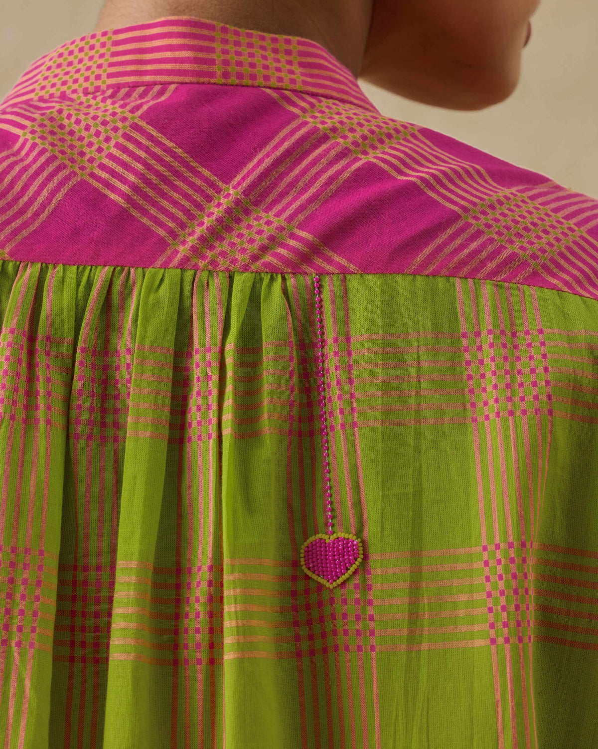Close-up of berry and lime mandarin collar top back with a beaded heart charm.