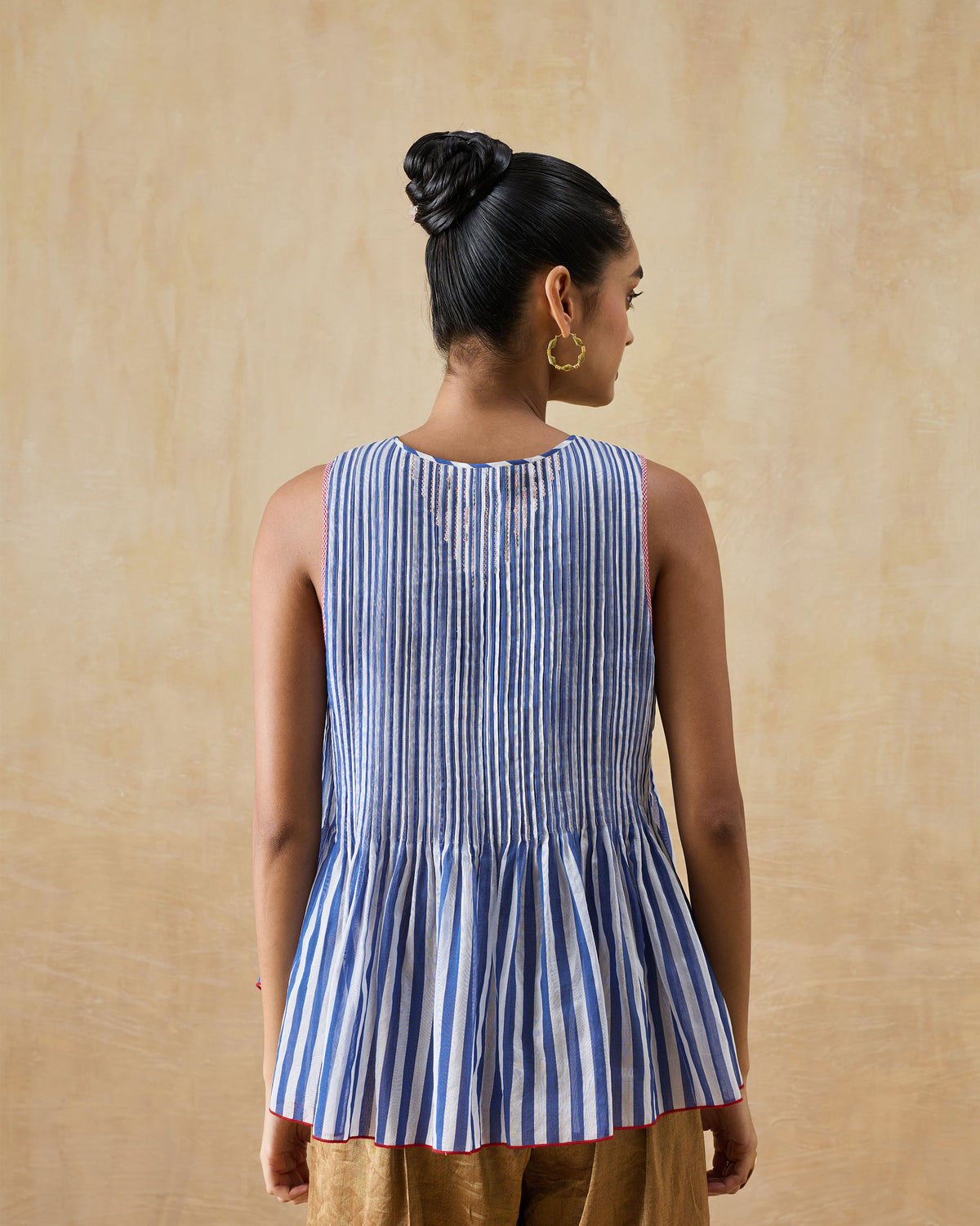 Back of a blue and white striped peplum top with red trim.