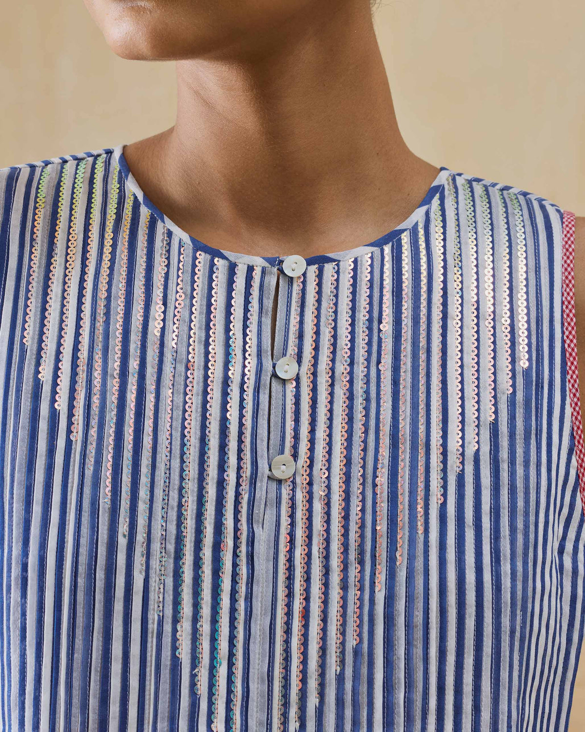 Close-up of a cobalt striped top with sequins and a button placket.