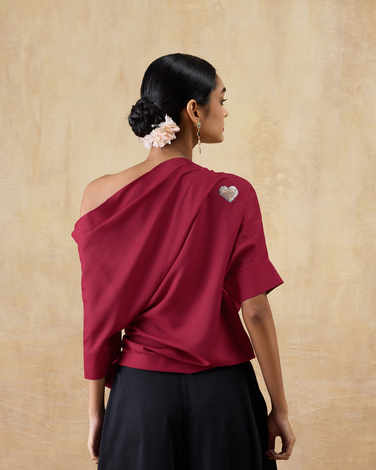 Back of a red one-shoulder Tokyo top with a sequinned heart motif.