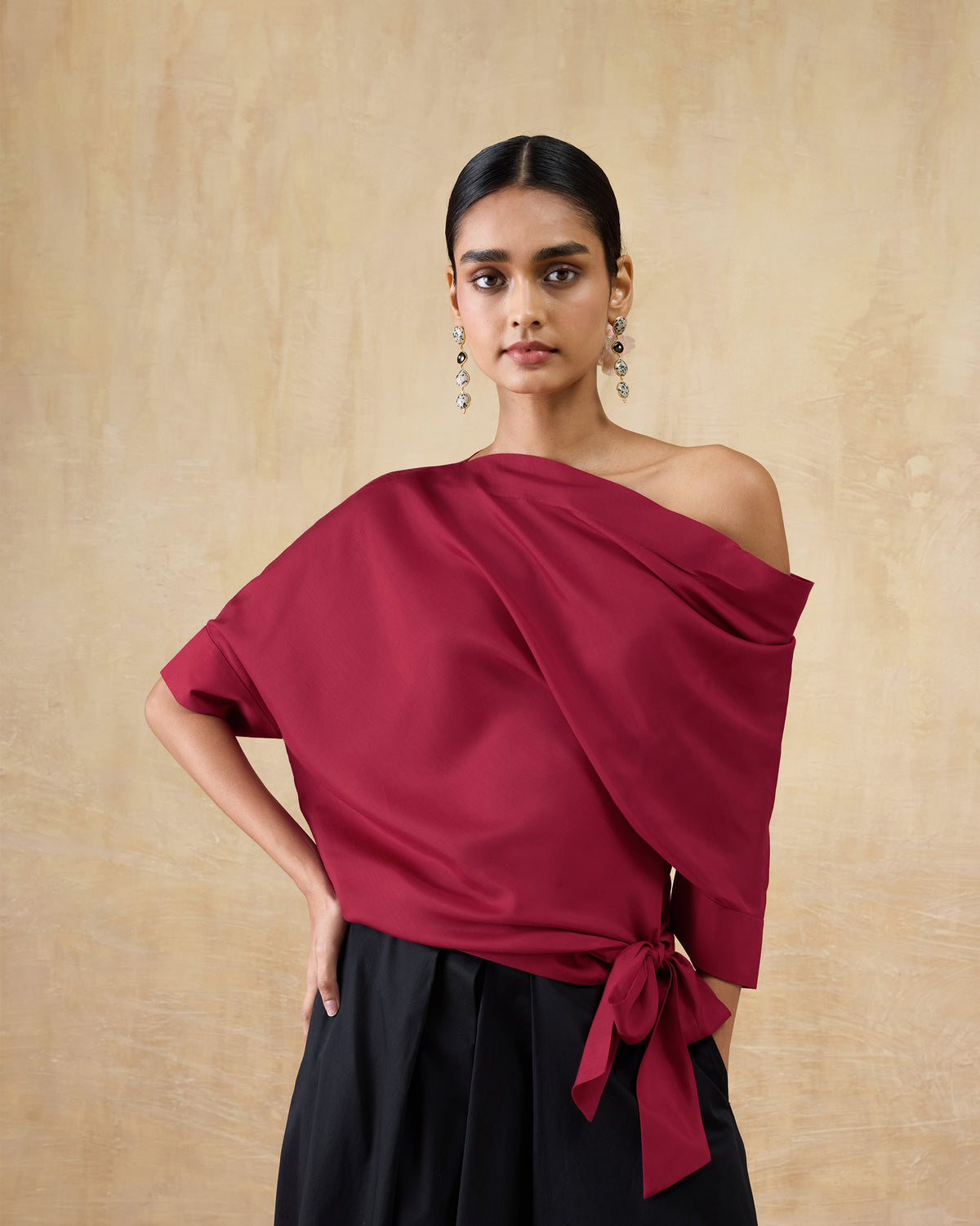 Person wearing a red draped Tokyo off-shoulder top with a side bow.